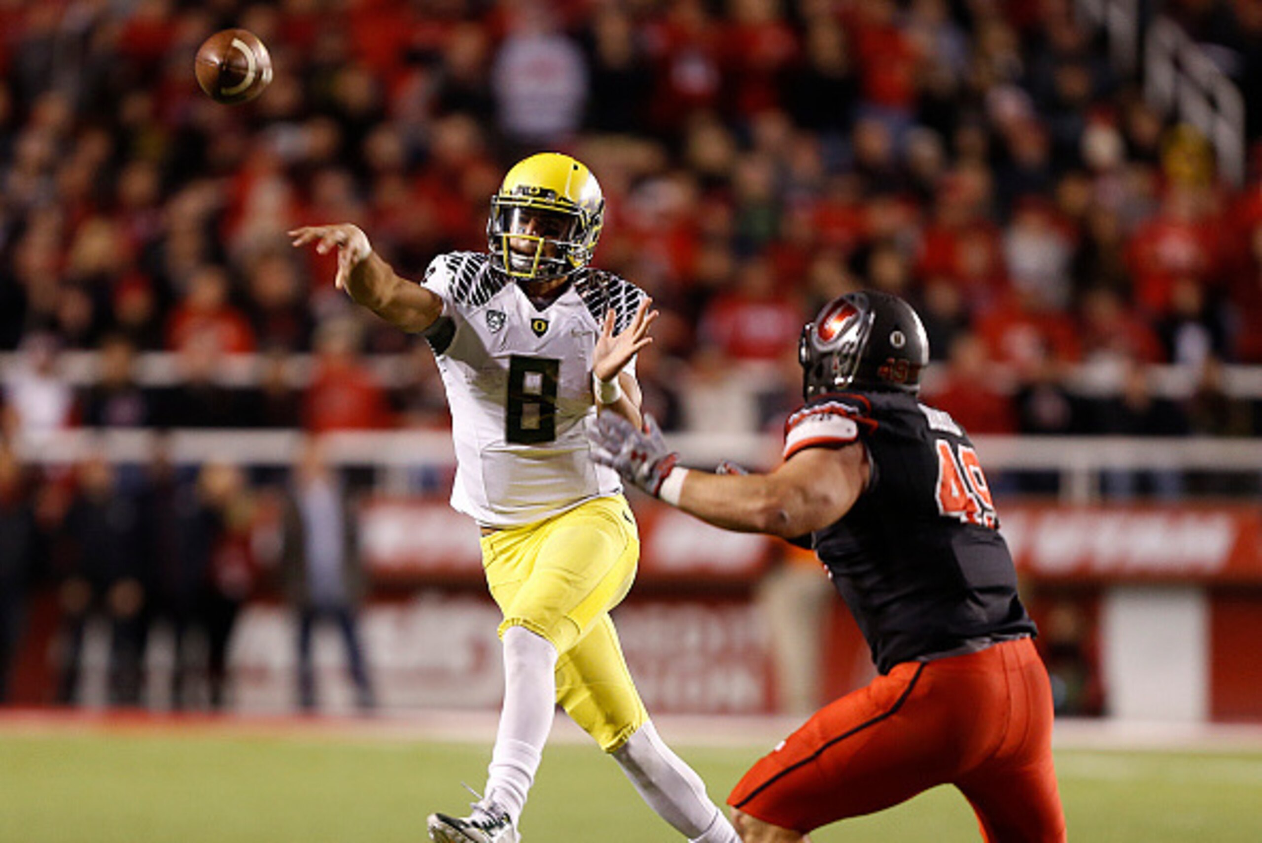 SALT LAKE CITY, UT - NOVEMBER 8:  Quarterback Marcus Mariota #8 of the Oregon Ducks throws a pass  as defensive end Hunter Dimick #49 of the Utah Utes  defends during the second half of an NCAA football game November 8, 2014 at Rice-Eccles Stadium in Salt