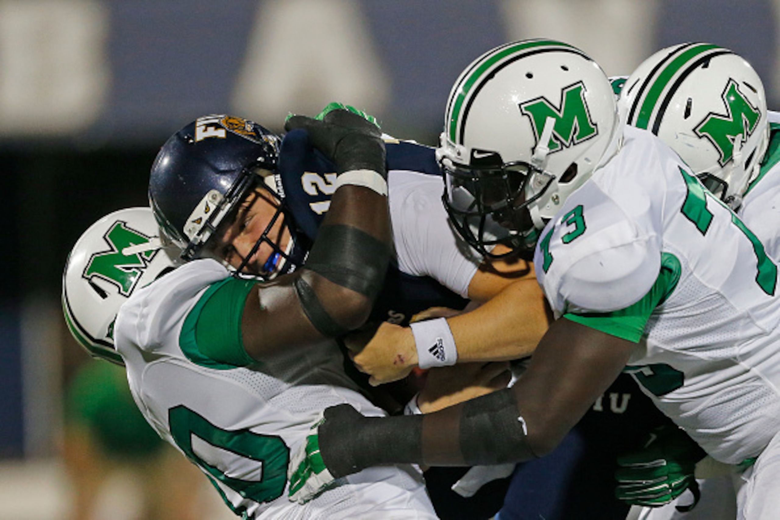 MIAMI, FL - OCTOBER 18: Alex McGough # 12 of the Florida International Panthers is sacked by Arnold Blackmon #90 and Joe Massaquoi #73 of the Marshall Thundering Herd on October 18, 2014 at FIU Stadium in Miami, Florida. Marshall defeated Florida Internat