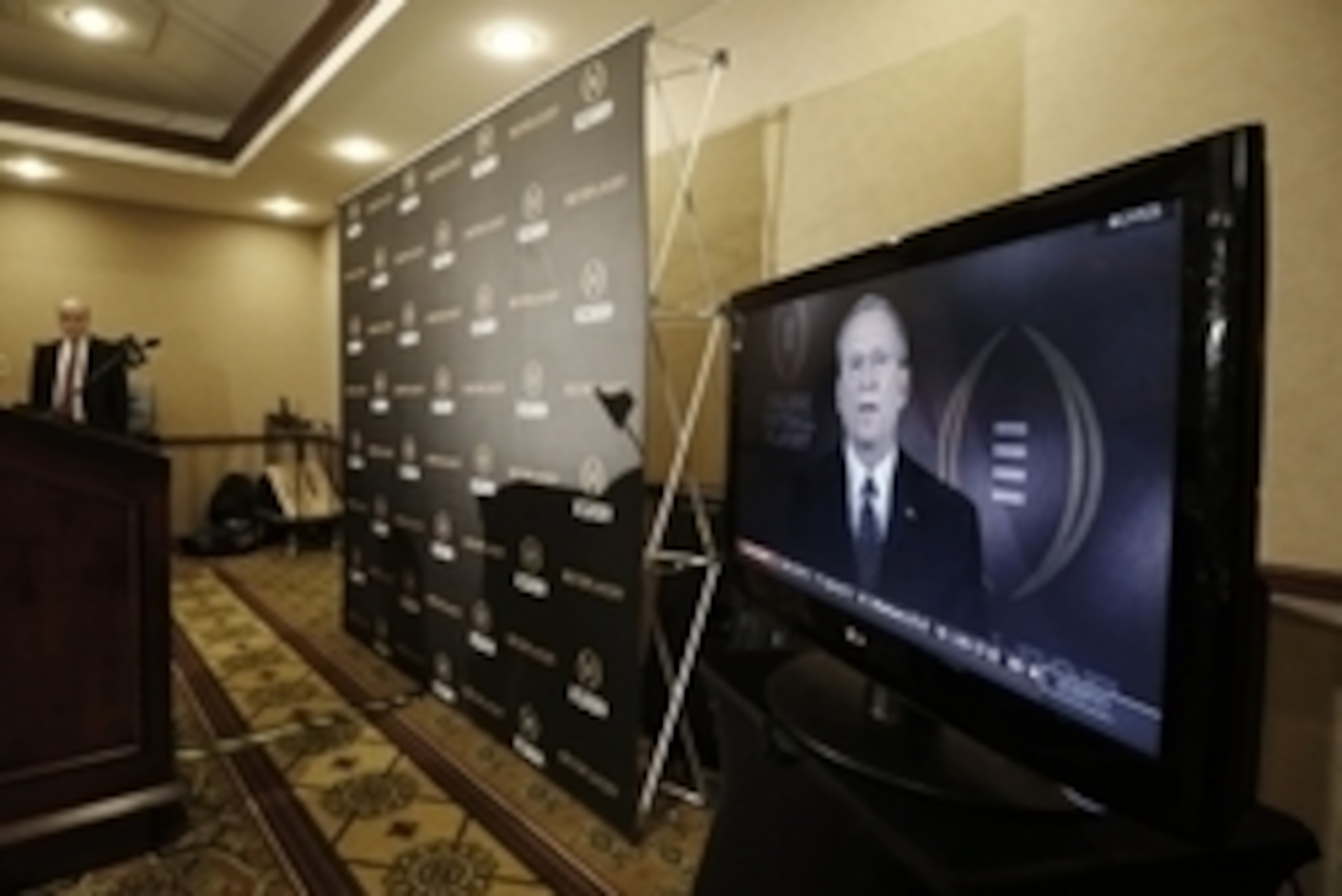 Oct 28, 2014; Grapevine, TX, USA;  Executive director Bill Hancock (back left) watches as selection committee chair Jeff Long (on tv)  unveils the top 25 teams in the initial college football playoff rankings at the Gaylord Texan Hotel. Mandatory Credit: 