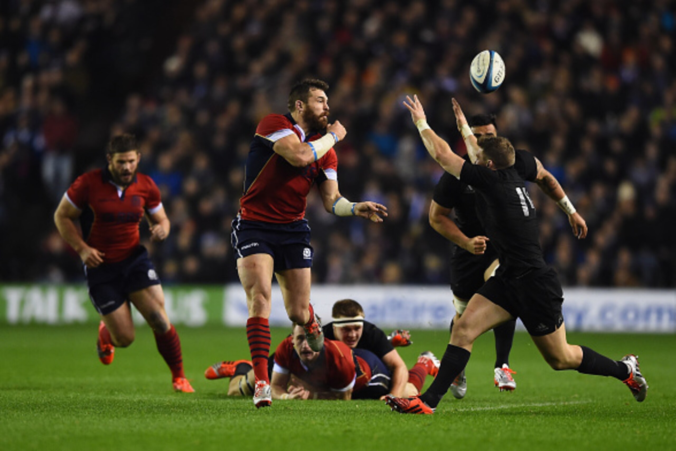EDINBURGH, SCOTLAND - NOVEMBER 15: Ross Ford of Scotland passes under pressure from Dan Carter of All Blacks during the Viagogo Autumn International match between Scotland and New Zealand at Murrayfield Stadium on November 15, 2014 in Edinburgh, Scotland.