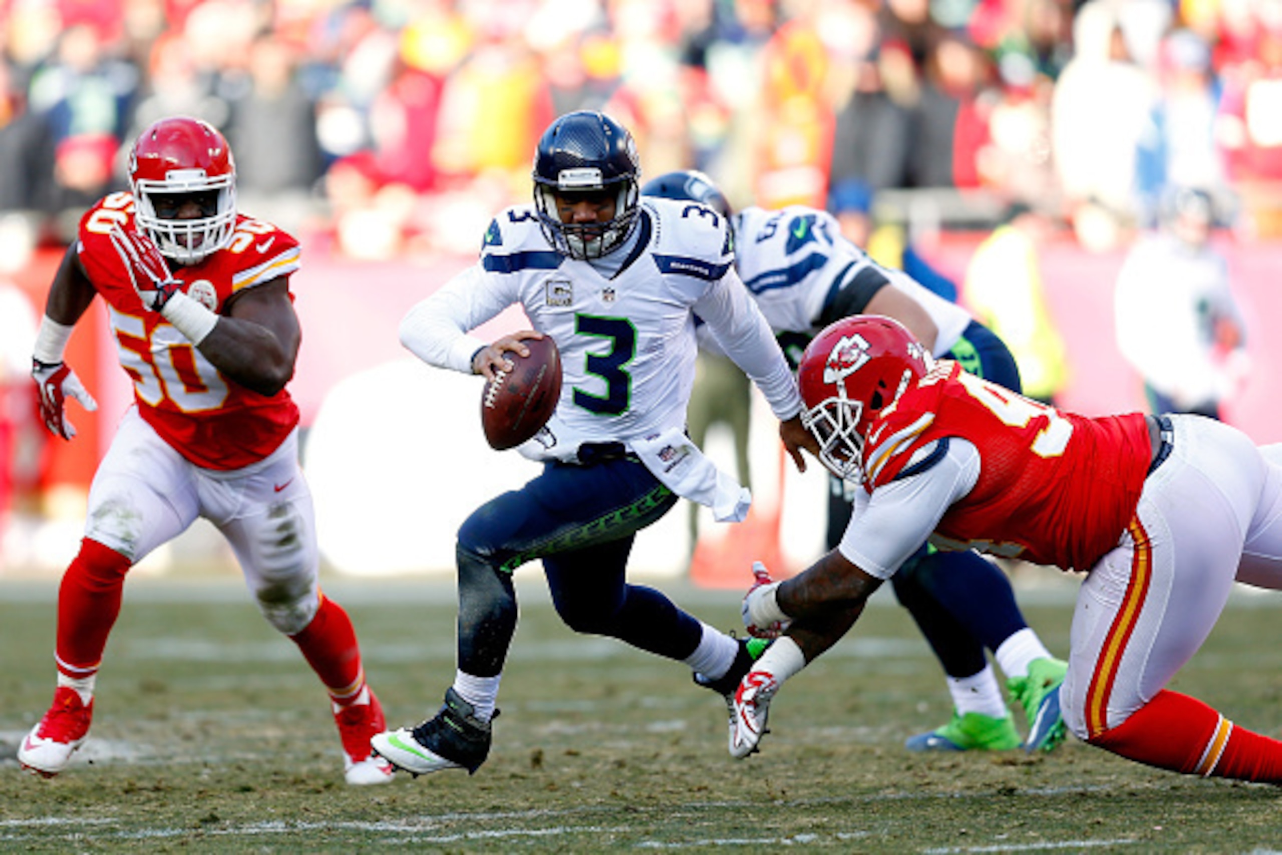 KANSAS CITY, MO - NOVEMBER 16:  Russell Wilson #3 of the Seattle Seahawks scrambles under pressure from Justin Houston #50 and Kevin Vickerson #94 of the Kansas City Chiefs during the game at Arrowhead Stadium on November 16, 2014 in Kansas City, Missouri