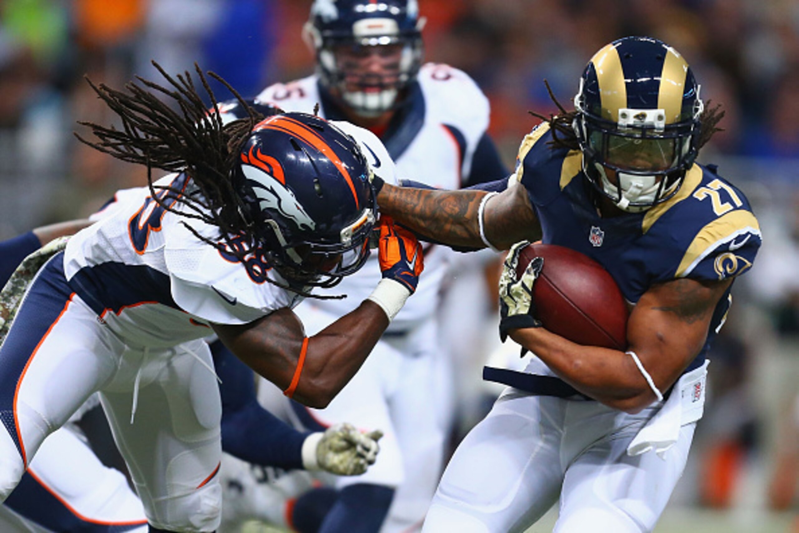 ST. LOUIS, MO - NOVEMBER 16: Tre Mason #27 of the St. Louis Rams slips a tackle attempt by Quinton Carter #38 of the Denver Broncos in the first quarter at the Edward Jones Dome on November 16, 2014 in St. Louis, Missouri.  The Rams beat the Broncos 22-7.