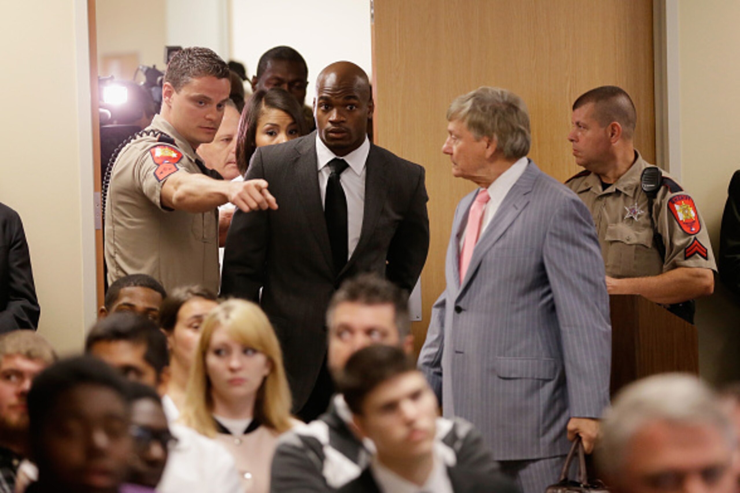 CONROE, TX - OCTOBER 08:  NFL player Adrian Peterson of the Minnesota Vikings enters the courtroom with his wife Ashley Brown and his attorney Rusty Hardin (R) at the Lee G. Alworth Building and the Montgomery County 9th District Court on October 8, 2014 