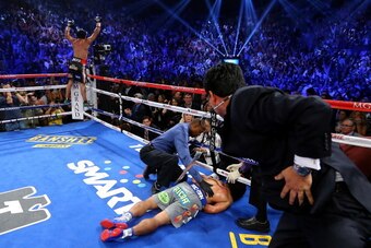 LAS VEGAS, NV - DECEMBER 08:  Manny Pacquiao lays face down on the mat after being knocked out in the sixth round as Juan Manuel Marquez celebrates during their welterweight bout at the MGM Grand Garden Arena on December 8, 2012 in Las Vegas, Nevada.  (Ph
