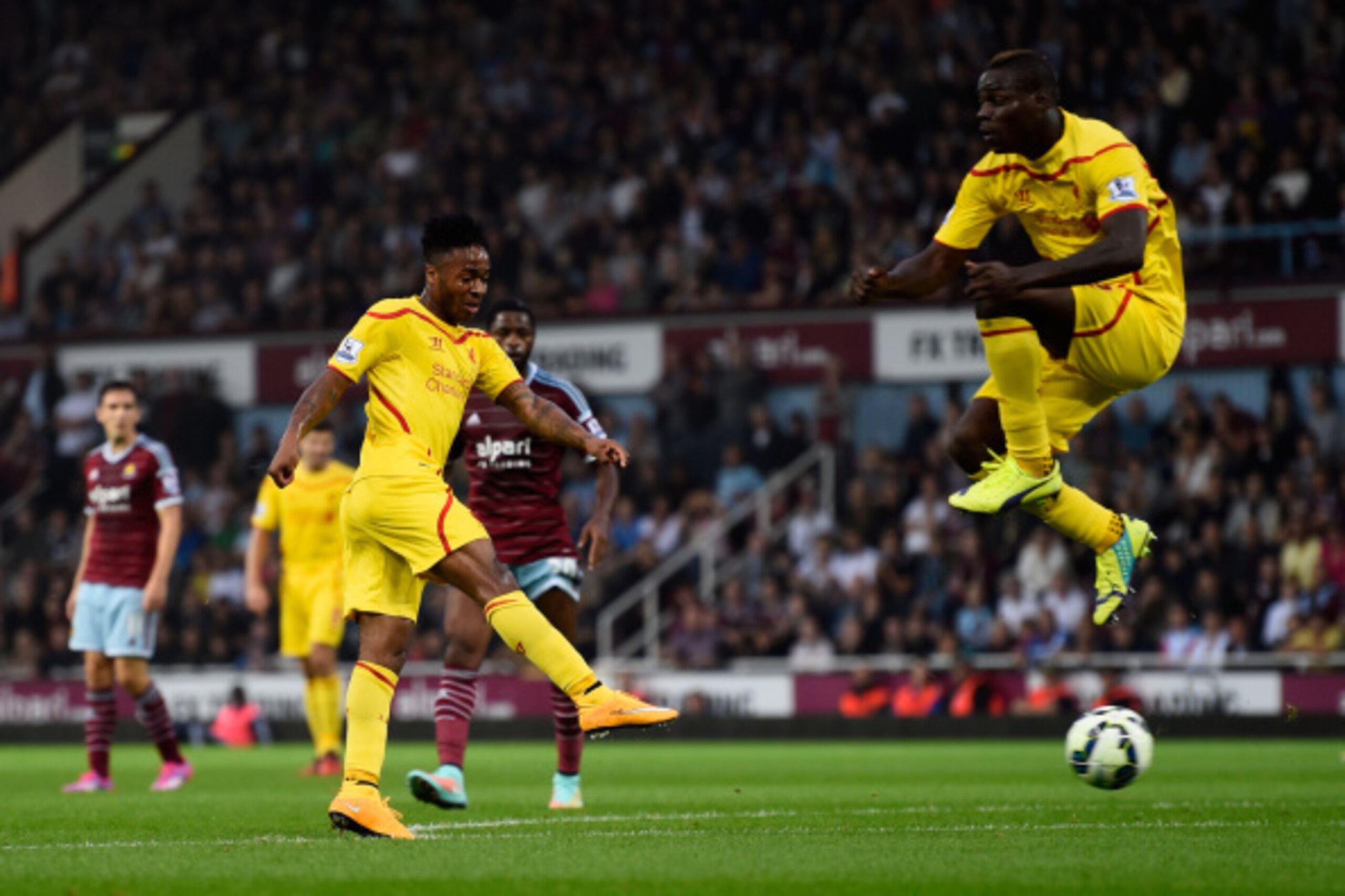 LONDON, ENGLAND - SEPTEMBER 20:  Raheem Sterling of Liverpool scores is team's first goal as teammate Mario Balotelli of Liverpool jumps to avoid the shot during the Barclays Premier League match between West Ham United and Liverpool at Boleyn Ground on S