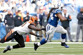 INDIANAPOLIS, IN - OCTOBER 19:  Trent Richardson #34 of the Indianapolis Colts slips past an attempted tackle by Robert Geathers #91 of the Cincinnati Bengals during the third quarter on October 19, 2014 at Lucas Oil Stadium on October 19, 2014 in Indiana