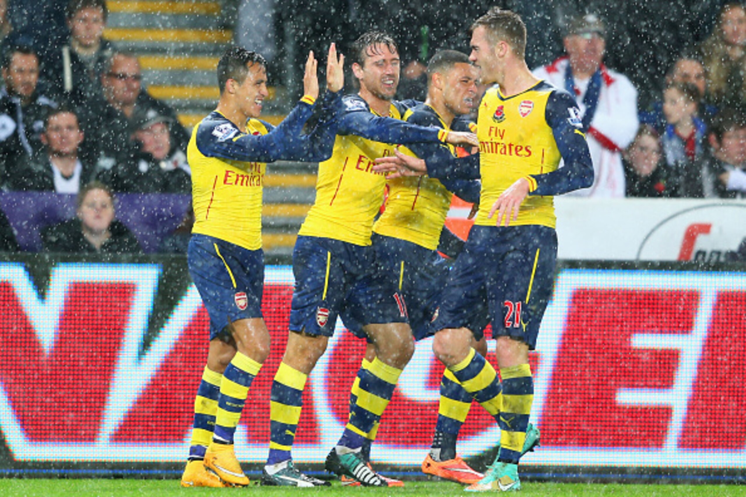 SWANSEA, WALES - NOVEMBER 09:  Alexis Sanchez of Arsenal (L) celebrates with team  mates as he scores their first goal during the Barclays Premier League match between Swansea City and Arsenal at Liberty Stadium on November 9, 2014 in Swansea, Wales.  (Ph