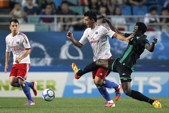 SUWON, SOUTH KOREA - JULY 20:  Tolgay Arslan (C) of Hamburger is challenged by Oluwafemi Ajilore (R) of FC Groningen during the Peace Cup match between Hamburger SV and FC Groningen at Suwon World Cup Stadium on July 20, 2012 in Suwon, South Korea.  (Phot