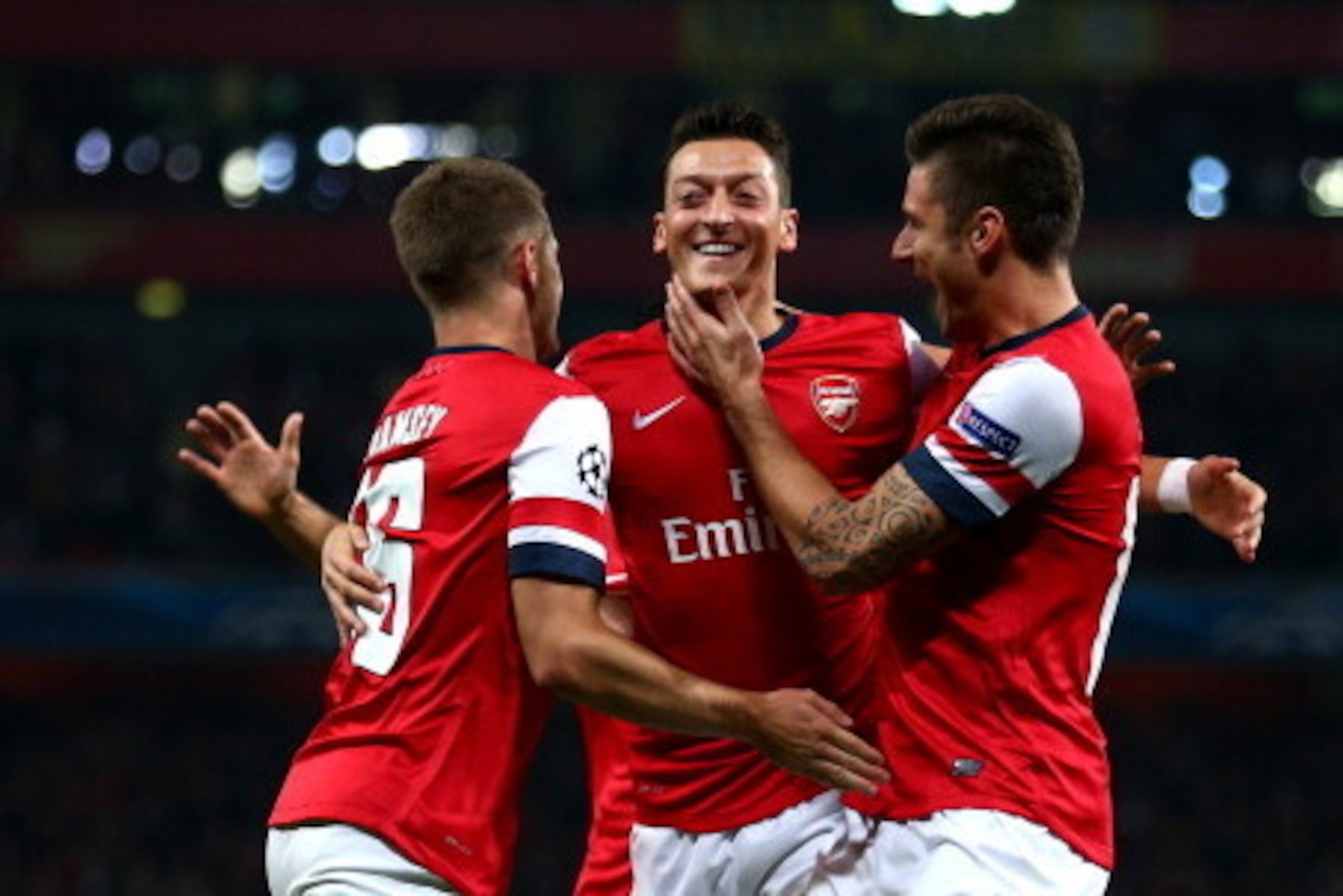 LONDON, ENGLAND - OCTOBER 01:  Mesut Oezil (C)of Arsenal is congratulated by teammates Aaron Ramsey (L) and Olivier Giroud (R) after scoring the opening goal during UEFA Champions League Group F match between Arsenal FC and SSC Napoli at Emirates Stadium 