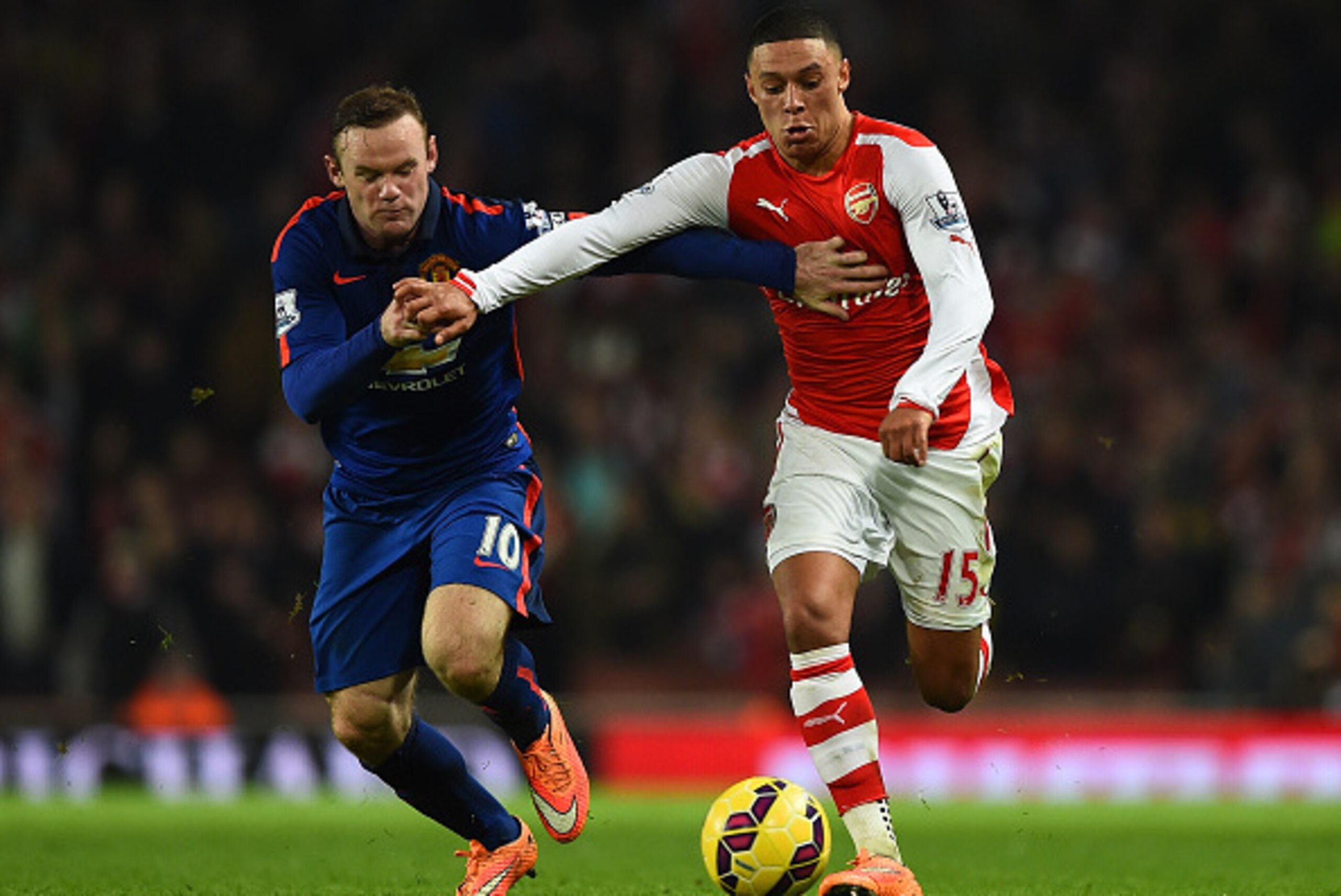 LONDON, ENGLAND - NOVEMBER 22:  Alex Oxlade-Chamberlain of Arsenal (R) is challenged by Wayne Rooney of Manchester United during the Barclays Premier League match between Arsenal and Manchester United at Emirates Stadium on November 22, 2014 in London, En