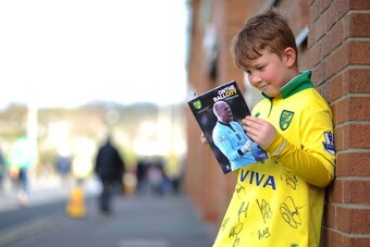 NORWICH, ENGLAND - APRIL 05:  A boy reads his matchday programme prior to the Barclays Premier League match between Norwich City and West Bromwich Albion at Carrow Road on April 05, 2014 in Norwich, England. (Photo by Tom Dulat/Getty Images)
