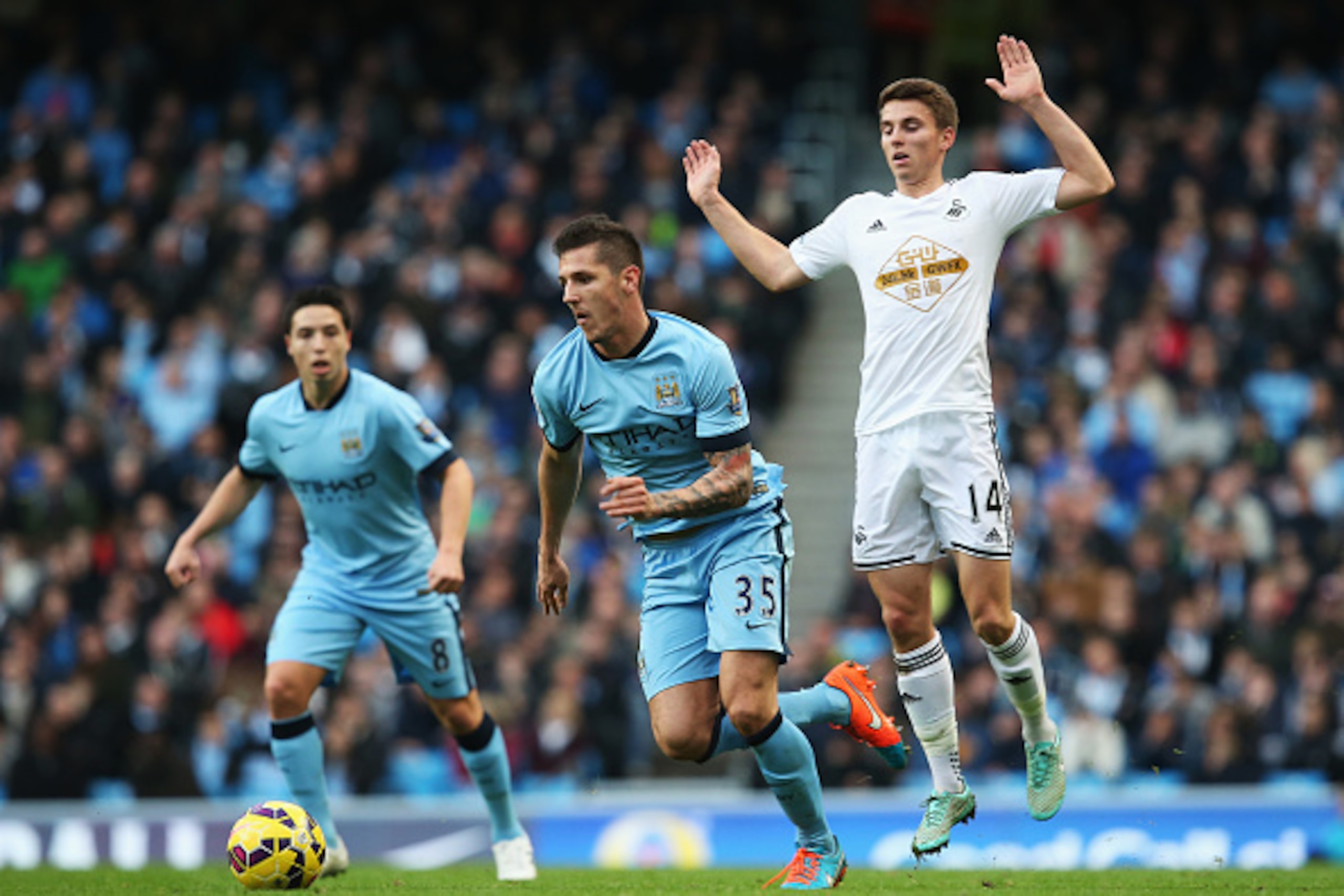 MANCHESTER, ENGLAND - NOVEMBER 22:  Tommy Carroll of Swansea City challenges Stevan Jovetic of Manchester City during the Barclays Premier League match between Manchester City and Swansea City at Etihad Stadium on November 22, 2014 in Manchester, England.