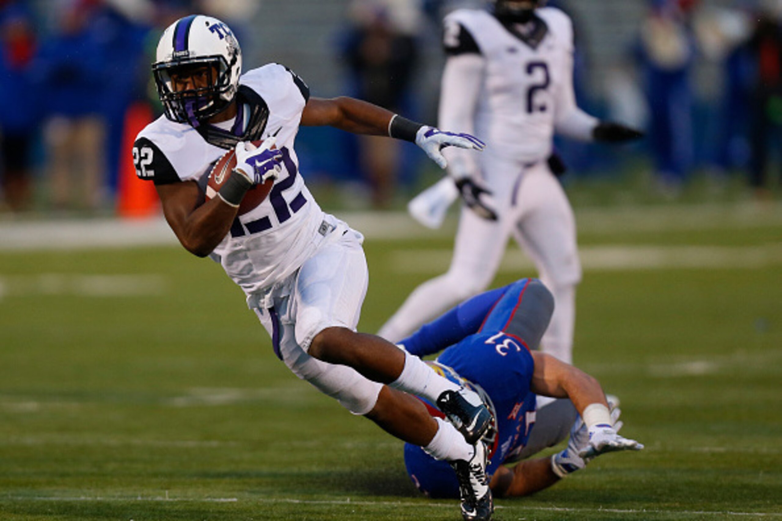 LAWRENCE, KS - NOVEMBER 15:  Aaron Green #22 of the TCU Horned Frogs gets past Ben Heeney #31 of the Kansas Jayhawks as he runs for a 24-yard touchdown in third quarter at Memorial Stadium on November 15, 2014 in Lawrence, Kansas. TCU won 34-30. (Photo by