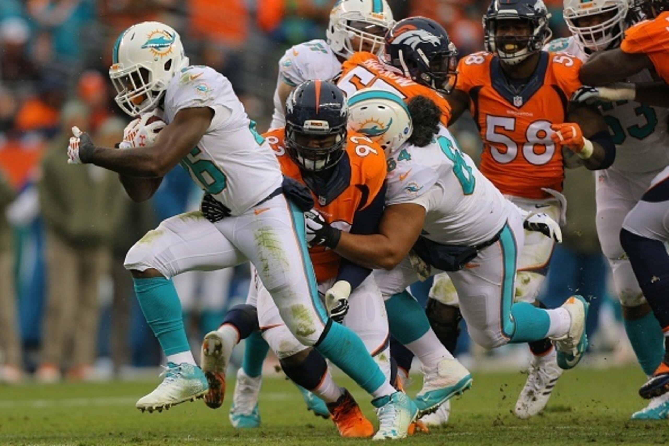 DENVER, CO - NOVEMBER 23:  Running back Lamar Miller #26 of the Miami Dolphins rushes against the Denver Broncos during a game at Sports Authority Field at Mile High on November 23, 2014 in Denver, Colorado.  (Photo by Justin Edmonds/Getty Images)