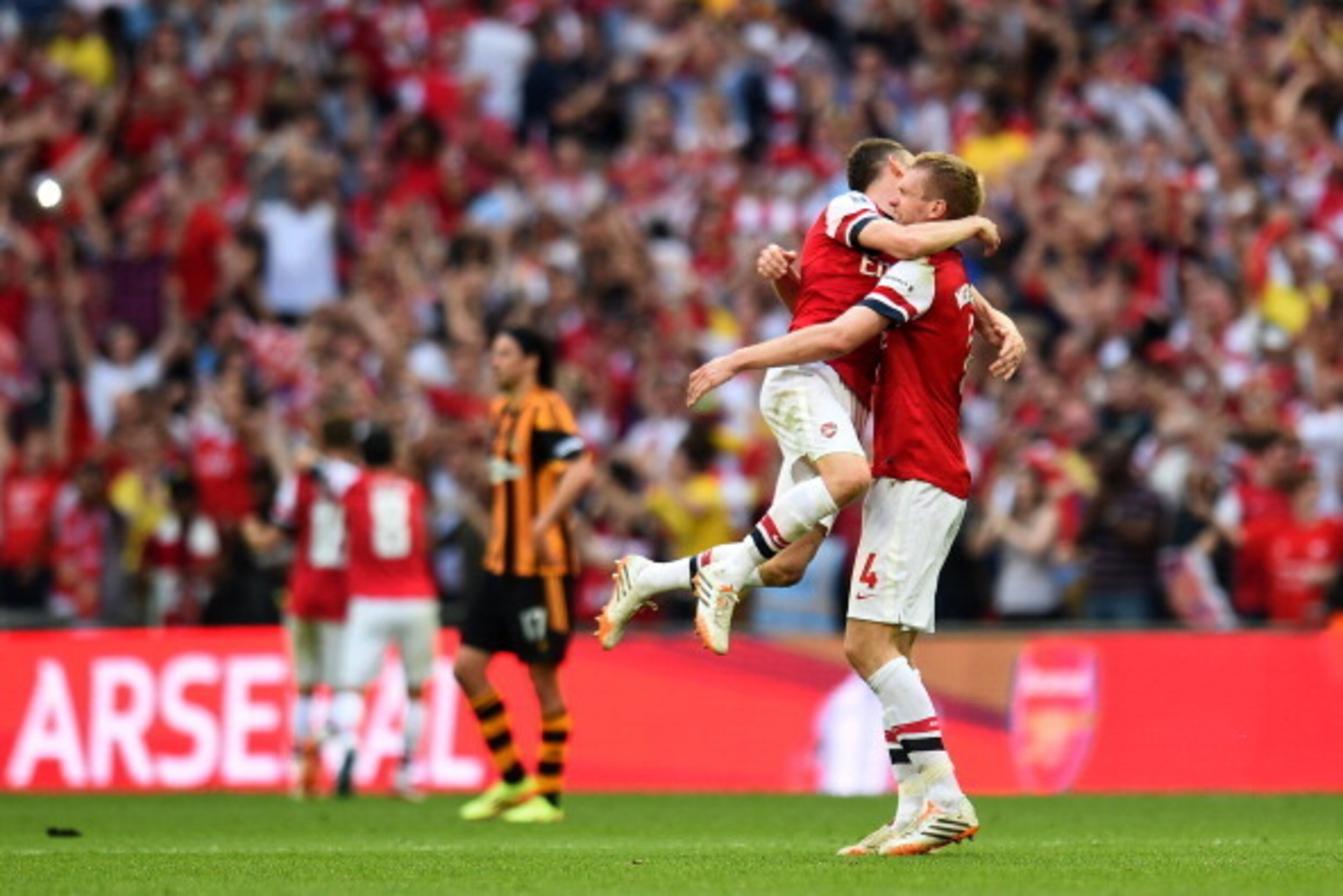 LONDON, ENGLAND - MAY 17:  Despair for Hull City as Laurent Koscielny and Per Mertesacker of Arsenal celebrate victory after the FA Cup with Budweiser Final match between Arsenal and Hull City at Wembley Stadium on May 17, 2014 in London, England.  (Photo