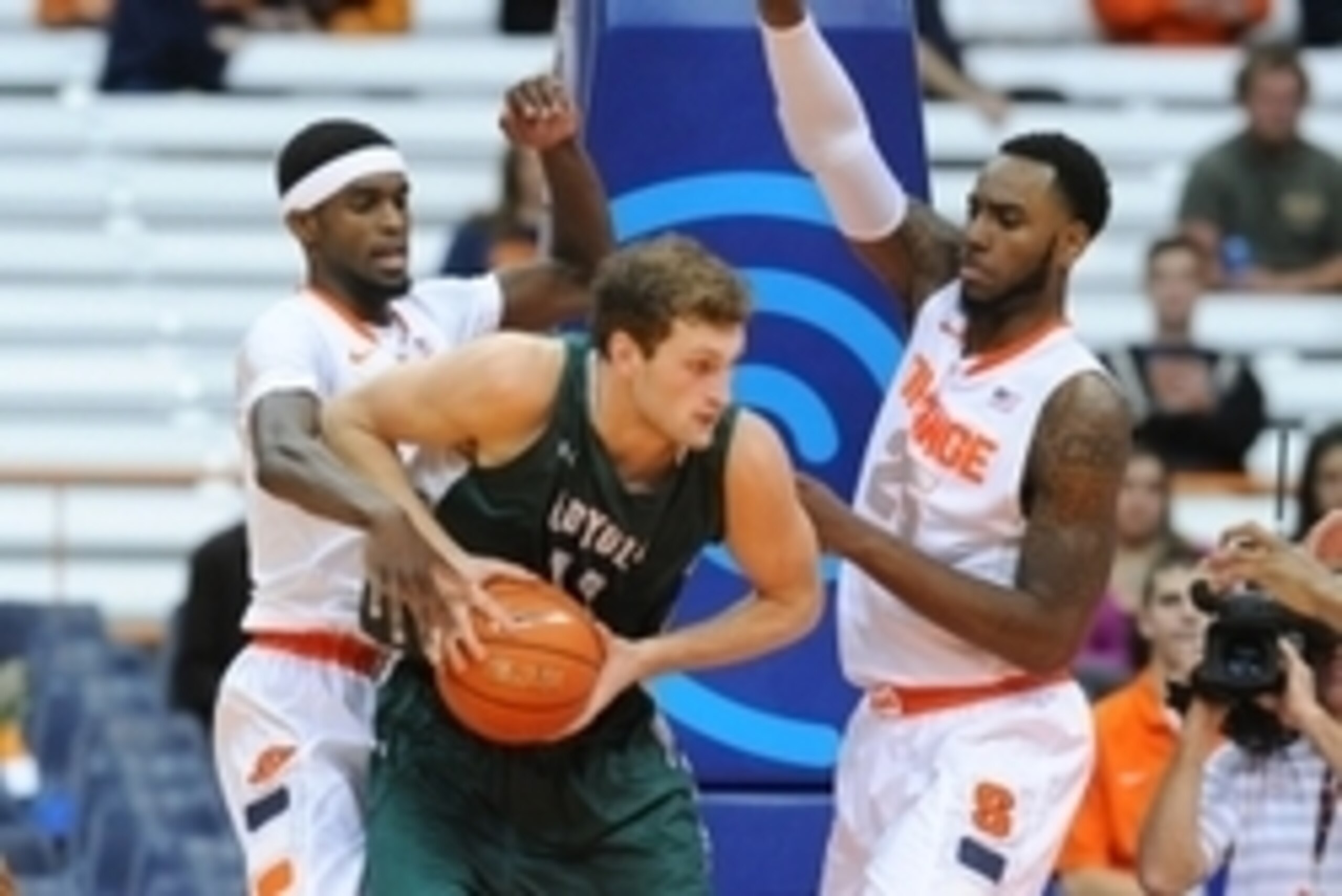 Nov 25, 2014; Syracuse, NY, USA; Loyola (Md) Greyhounds forward Franz Rassman (C) drives to the basket against the defense of Syracuse Orange forwards B.J. Johnson (L) and Rakeem Christmas (R) during the first half at the Carrier Dome.  Mandatory Credit: 