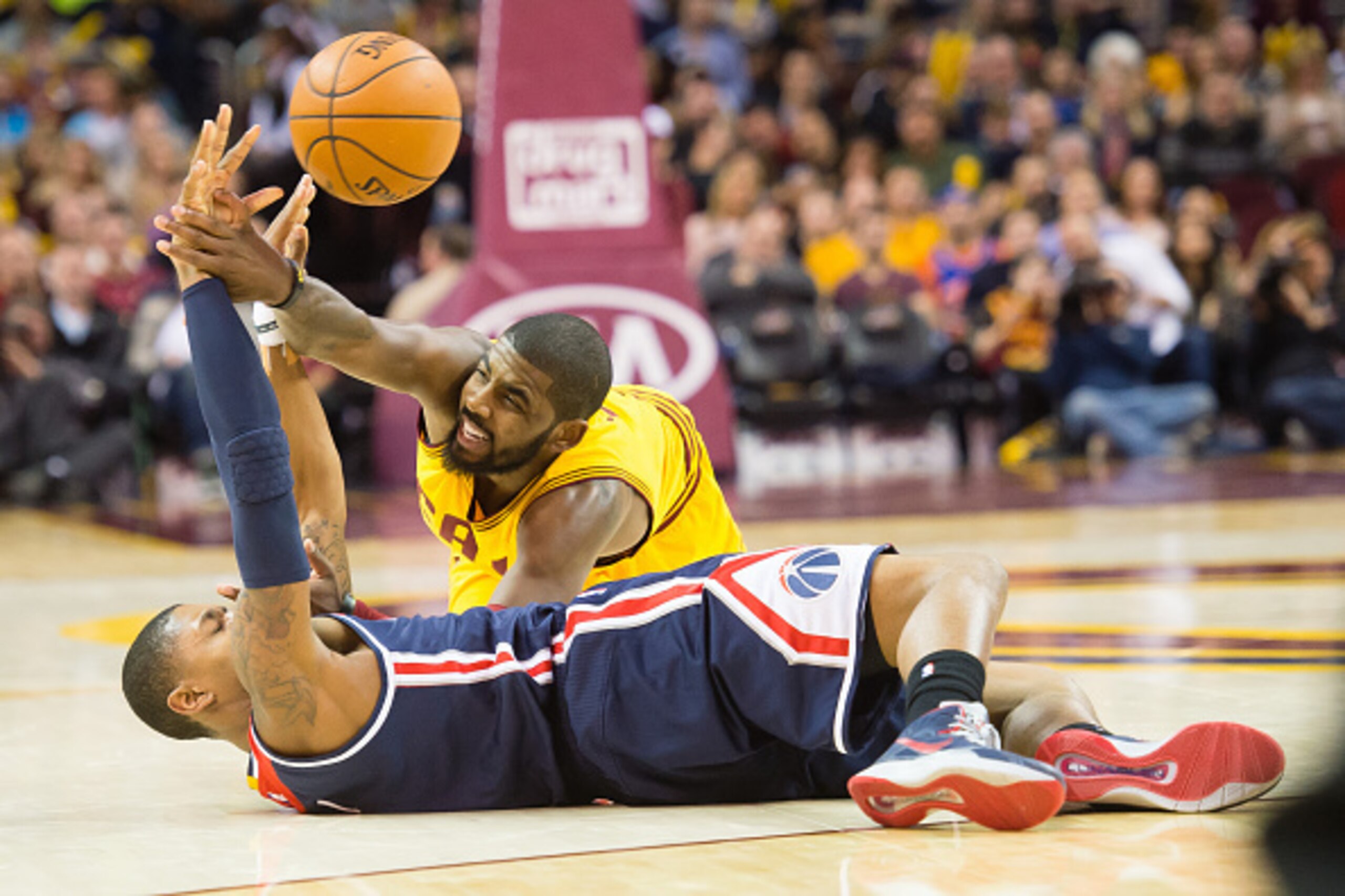 CLEVELAND, OH - NOVEMBER 26: Bradley Beal #3 of the Washington Wizards makes a pass from the ground while under pressure from Kyrie Irving #2 of the Cleveland Cavaliers during the second half at Quicken Loans Arena on November 26, 2014 in Cleveland, Ohio.