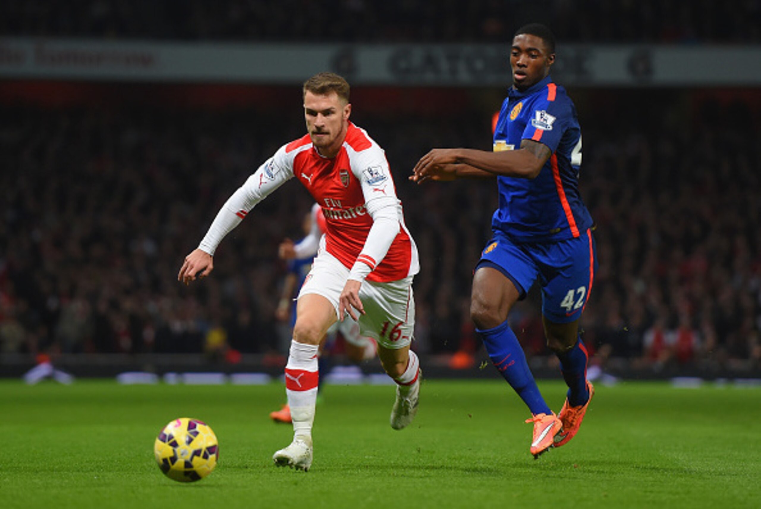 LONDON, ENGLAND - NOVEMBER 22:  Aaron Ramsey of Arsenal and Tyler Blackett of Manchester United battle for the ball during the Barclays Premier League match between Arsenal and Manchester United at Emirates Stadium on November 22, 2014 in London, England.
