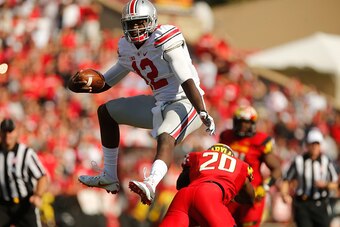 COLLEGE PARK, MD - OCTOBER 04:  Quarterback Cardale Jones #12 of the Ohio State Buckeyes hurdles safety Anthony Nixon #20 of the Maryland Terrapins during the fourth quarter of Ohio State's 52-24 win at Byrd Stadium on October 4, 2014 in College Park, Mar