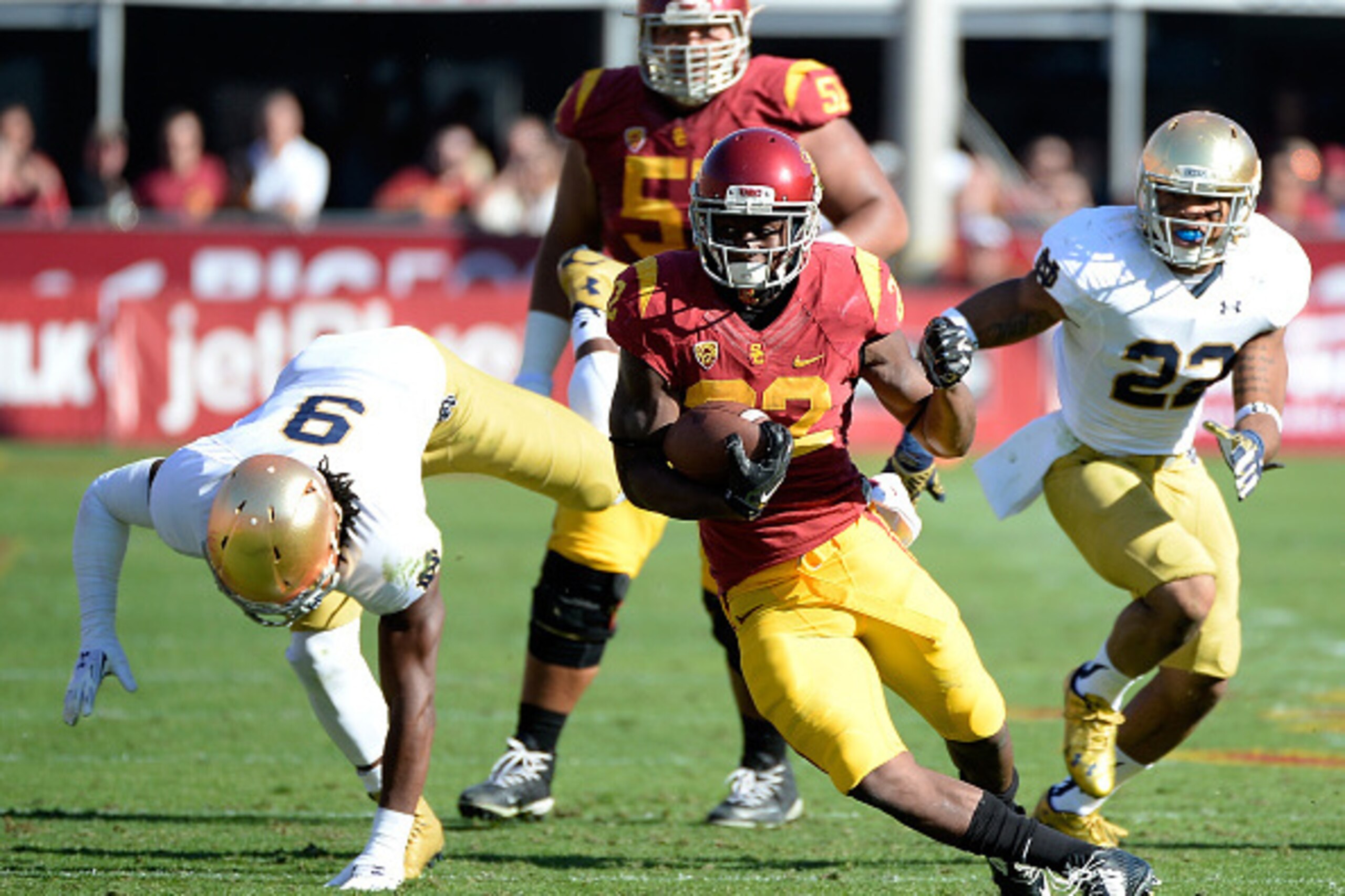 LOS ANGELES, CA - NOVEMBER 29:  Justin Davis #22 of the USC Trojans runs for a first down between Jaylon Smith #9 and Elijah Shumate #22 of the Notre Dame Fighting Irish during the first quarter at Los Angeles Memorial Coliseum on November 29, 2014 in Los