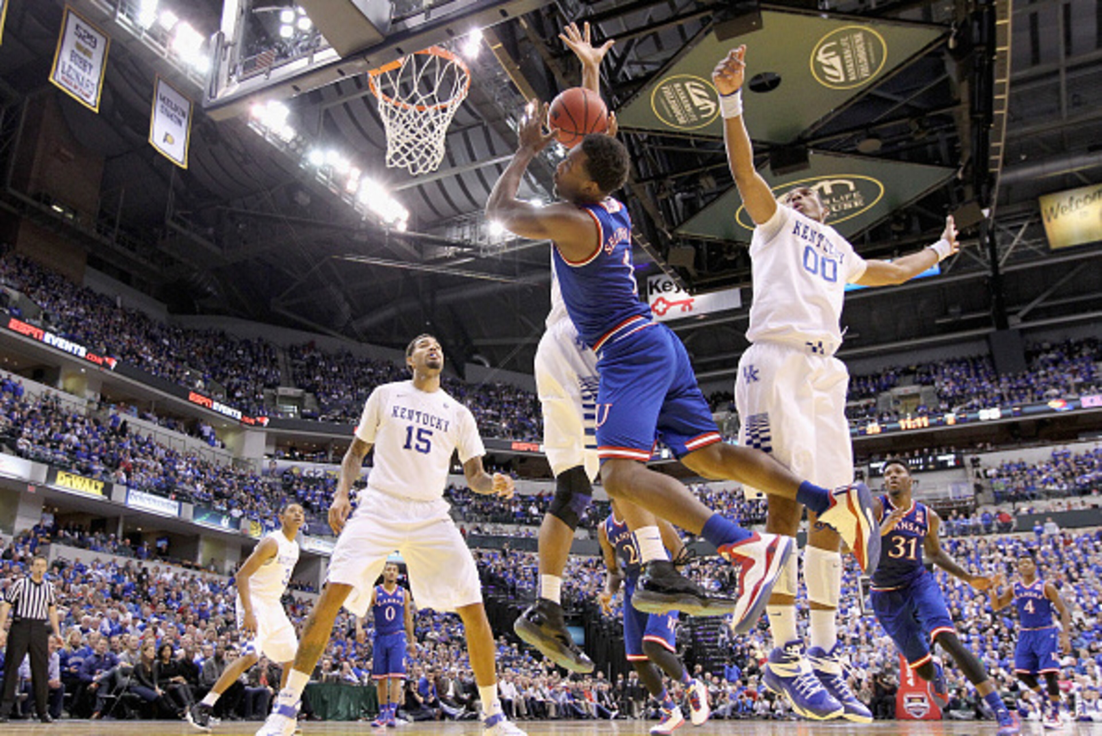 INDIANAPOLIS, IN - NOVEMBER 18: Wayne Seldon #1 of the Kansas Jayhawks loses control of the ball  while defended by Trey Lyles #41 and Marcus Lee #00 of the Kentucky Wildcats in the State Farm Champions Classic at Bankers Life Fieldhouse on November 18, 2
