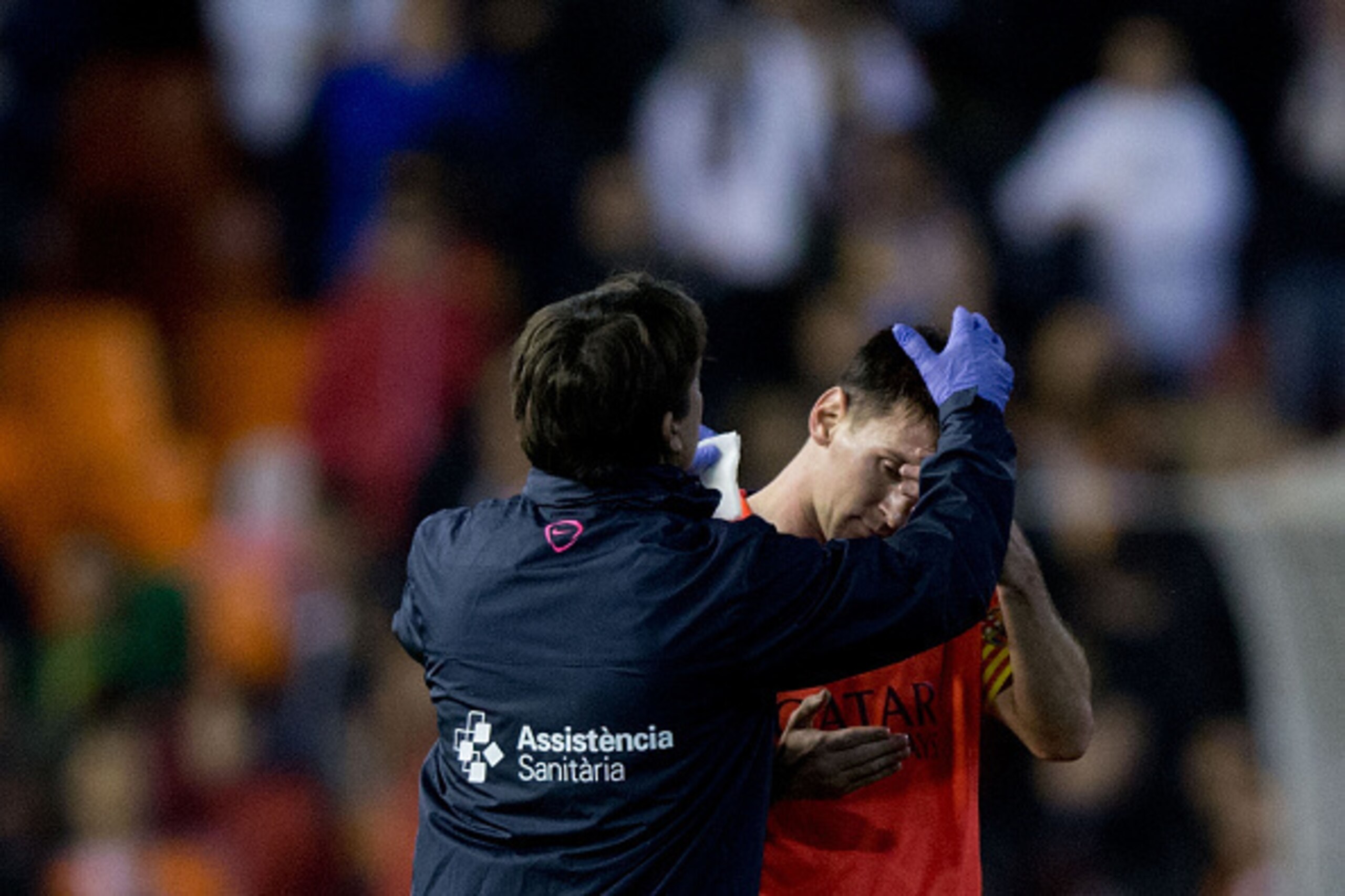 VALENCIA, SPAIN - NOVEMBER 30:  A medical assistant treat Lionel Messi of FC Barcelona after being blown with a bottle after the La Liga match between Valencia CF and FC Barcelona at Estadi de Mestalla on November 30, 2014 in Valencia, Spain.  (Photo by G