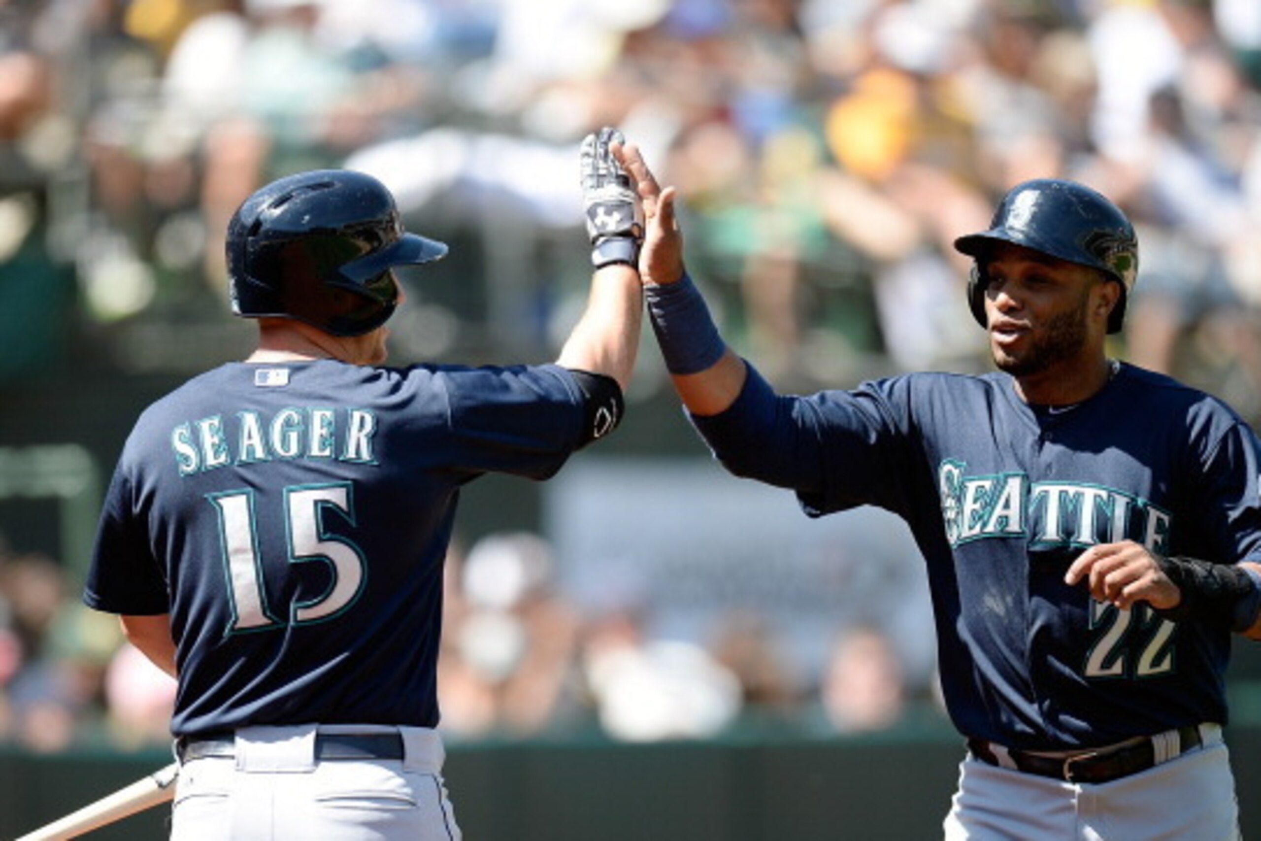 OAKLAND, CA - APRIL 06:  Robinson Cano #22 of the Seattle Mariners is congratulated by Kyle Seager #15 after Cano scored against the Oakland Athletics in the top of the third inning at O.co Coliseum on April 6, 2014 in Oakland, California. Cano scored on