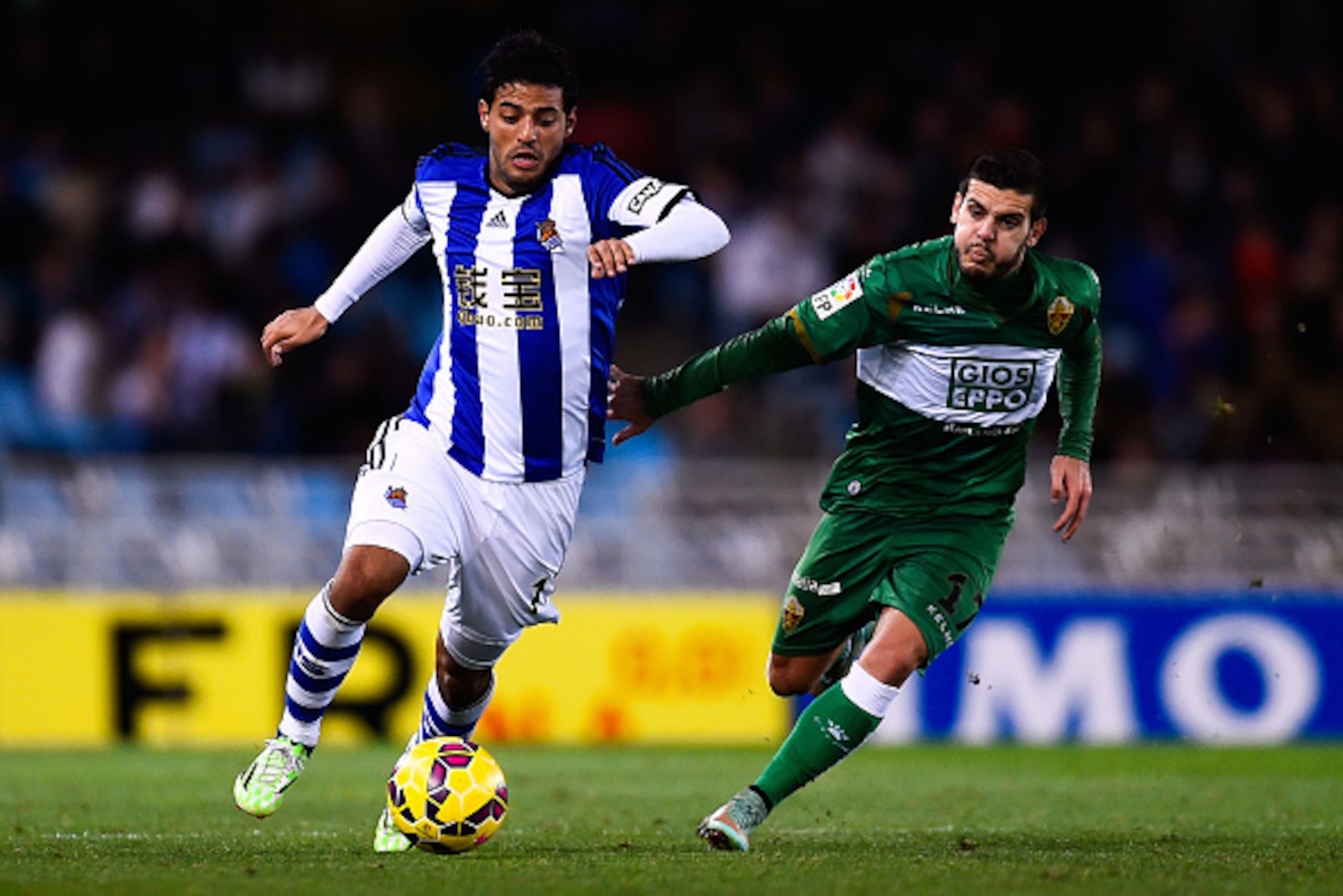 SAN SEBASTIAN, SPAIN - NOVEMBER 28:  Carlos Vela Garrido of Real Sociedad competes for the ball with Victor Rodriguez of Elche FC during the La Liga match between Real Socided and Elche FC at Estadio Anoeta on November 28, 2014 in San Sebastian, Spain.  (