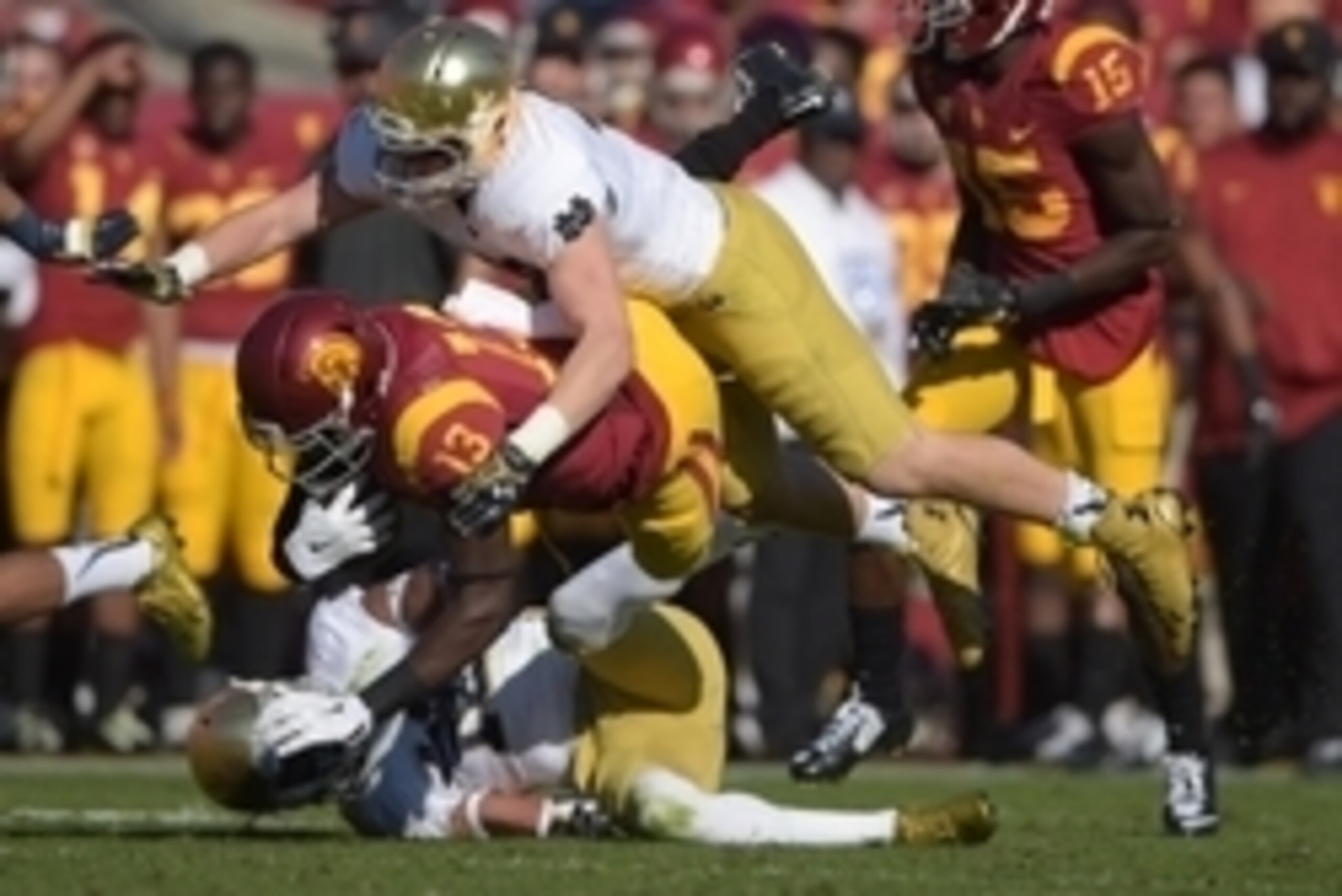 Nov 29, 2014; Los Angeles, CA, USA; Southern California Trojans tight end Bryce Dixon (13) is tackled by Notre Dame Fighting Irish linebacker Greer Martini (48) and safety Max Redfield (10) at Los Angeles Memorial Coliseum. Mandatory Credit: Kirby Lee-USA