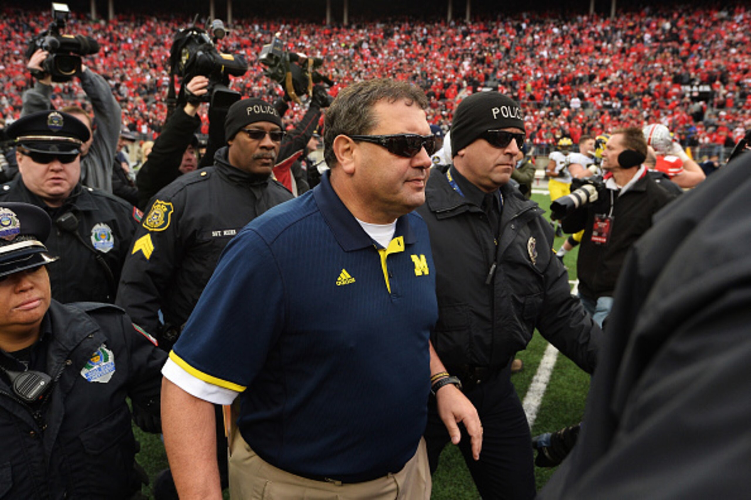 COLUMBUS, OH - NOVEMBER 29:  Head Coach Brady Hoke of the Michigan Wolverines is led off the field by security after his Wolverines lost to Ohio State 42-28 at Ohio Stadium on November 29, 2014 in Columbus, Ohio.   (Photo by Jamie Sabau/Getty Images)
