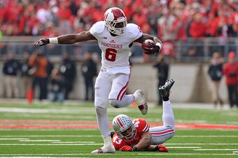 COLUMBUS, OH - NOVEMBER 22:  Tevin Coleman #6 of the Indiana Hoosiers leaps past the tackle attempt of Darron Lee #43 of the Ohio State Buckeyes in the second quarter at Ohio Stadium on November 22, 2014 in Columbus, Ohio. Coleman's three rushing touchdow