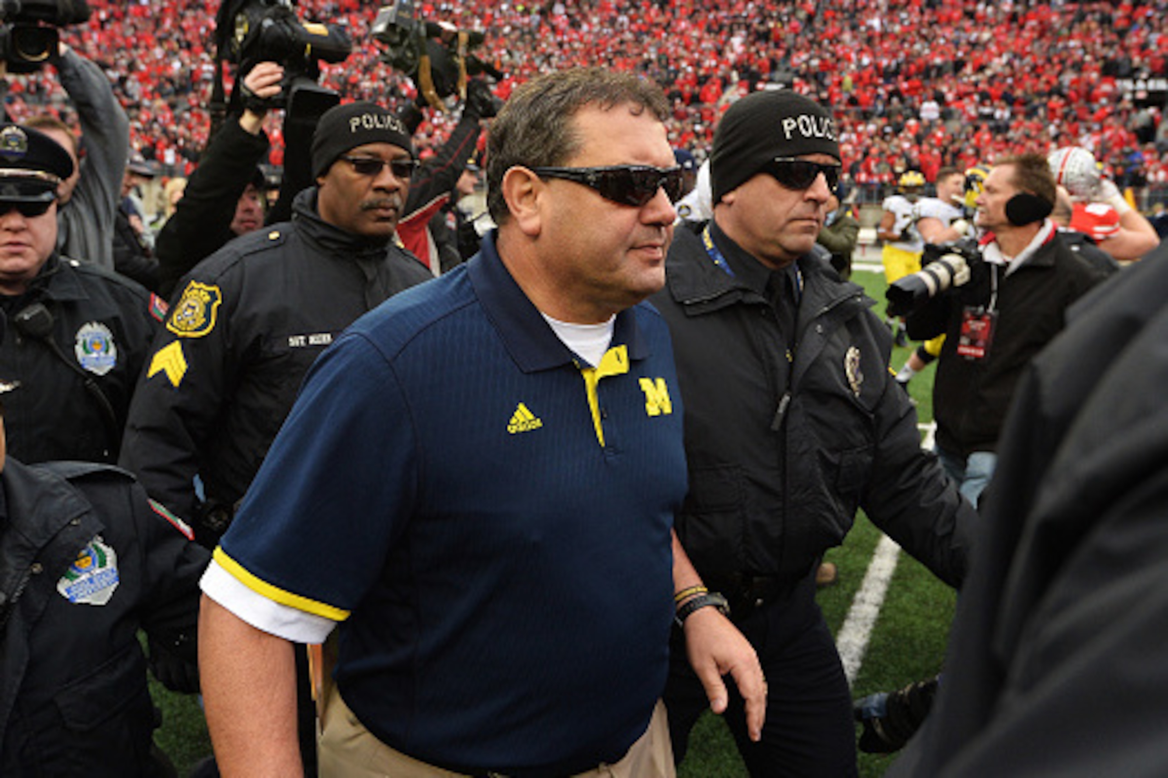 COLUMBUS, OH - NOVEMBER 29:  Head Coach Brady Hoke of the Michigan Wolverines is led off the field by security after his Wolverines lost to Ohio State 42-28 at Ohio Stadium on November 29, 2014 in Columbus, Ohio.   (Photo by Jamie Sabau/Getty Images)