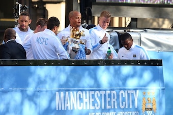 MANCHESTER, ENGLAND - MAY 12:  Vincent Kompany of Manchester City lifts the Barclays Premier League trophy aloft outside Manchester Town Hall as Joe Hart gives the thumbs up at the start of the Manchester City victory parade around the streets of Manchest