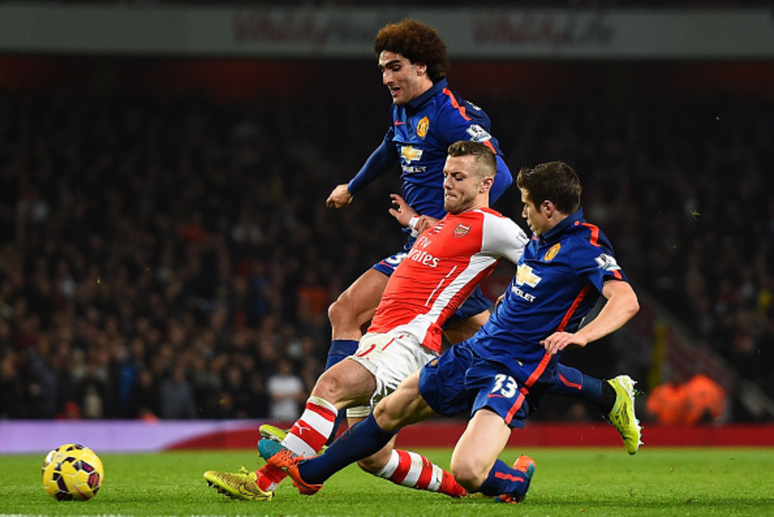 LONDON, ENGLAND - NOVEMBER 22: Jack Wilshere of Arsenal is tackled by Marouane Fellaini of Manchester United (L) and Paddy McNair of Manchester United during the Barclays Premier League match between Arsenal and Manchester United at Emirates Stadium on No