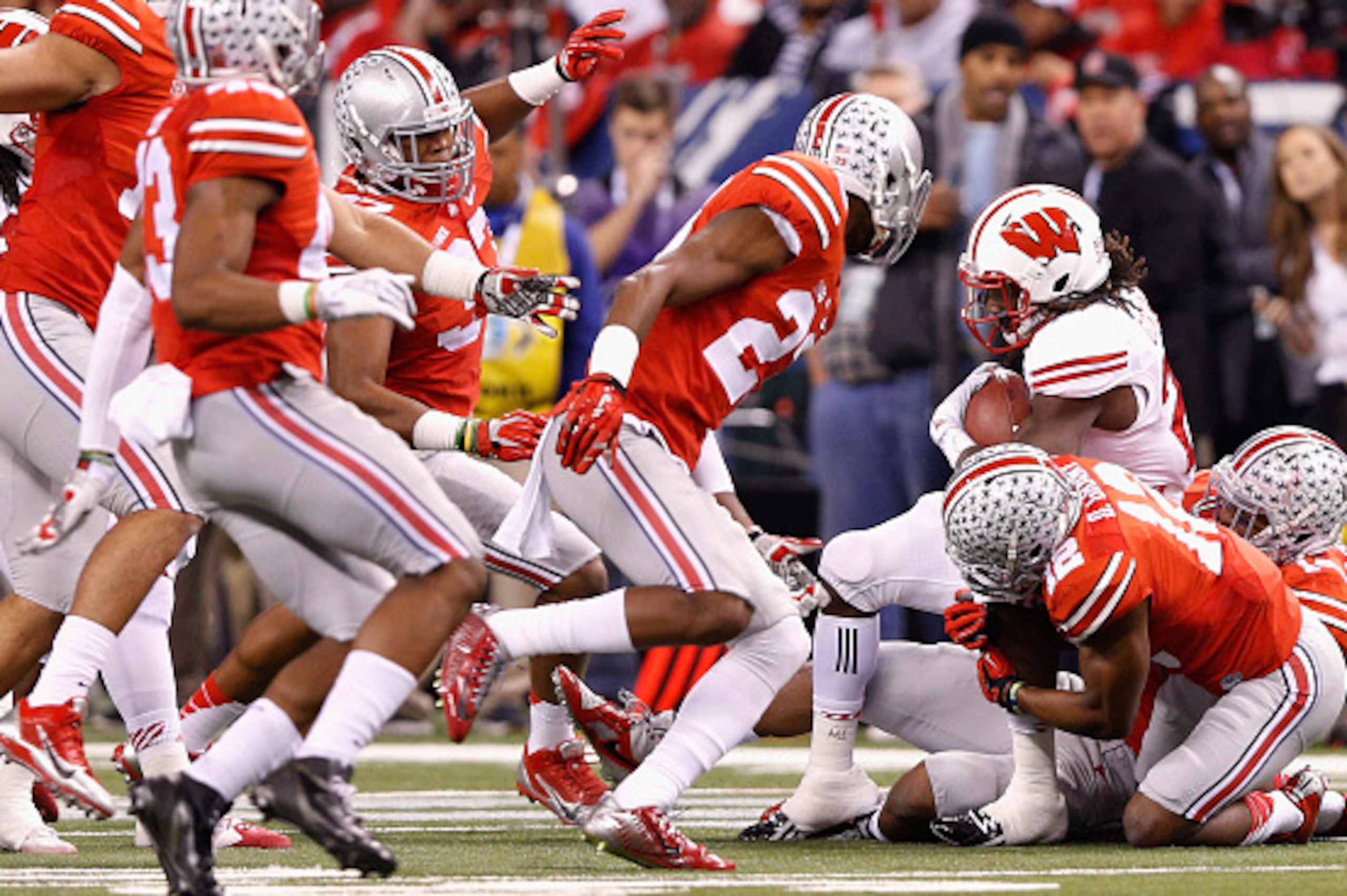 INDIANAPOLIS, IN - DECEMBER 06:  Melvin Gordon #25 of the Wisconsin Badgers is tackled by the Ohio State Buckeyes during the second quarter of the Big Ten Championship at Lucas Oil Stadium on December 6, 2014 in Indianapolis, Indiana.  (Photo by Joe Robbi