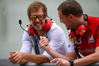ABU DHABI, UNITED ARAB EMIRATES - NOVEMBER 25:  Sebastian Vettel of Germany and Infiniti Red Bull Racing smiles as he speaks with members of the Ferrari team on the pit wall during day one of Formula One testing at Yas Marina Circuit on November 25, 2014 