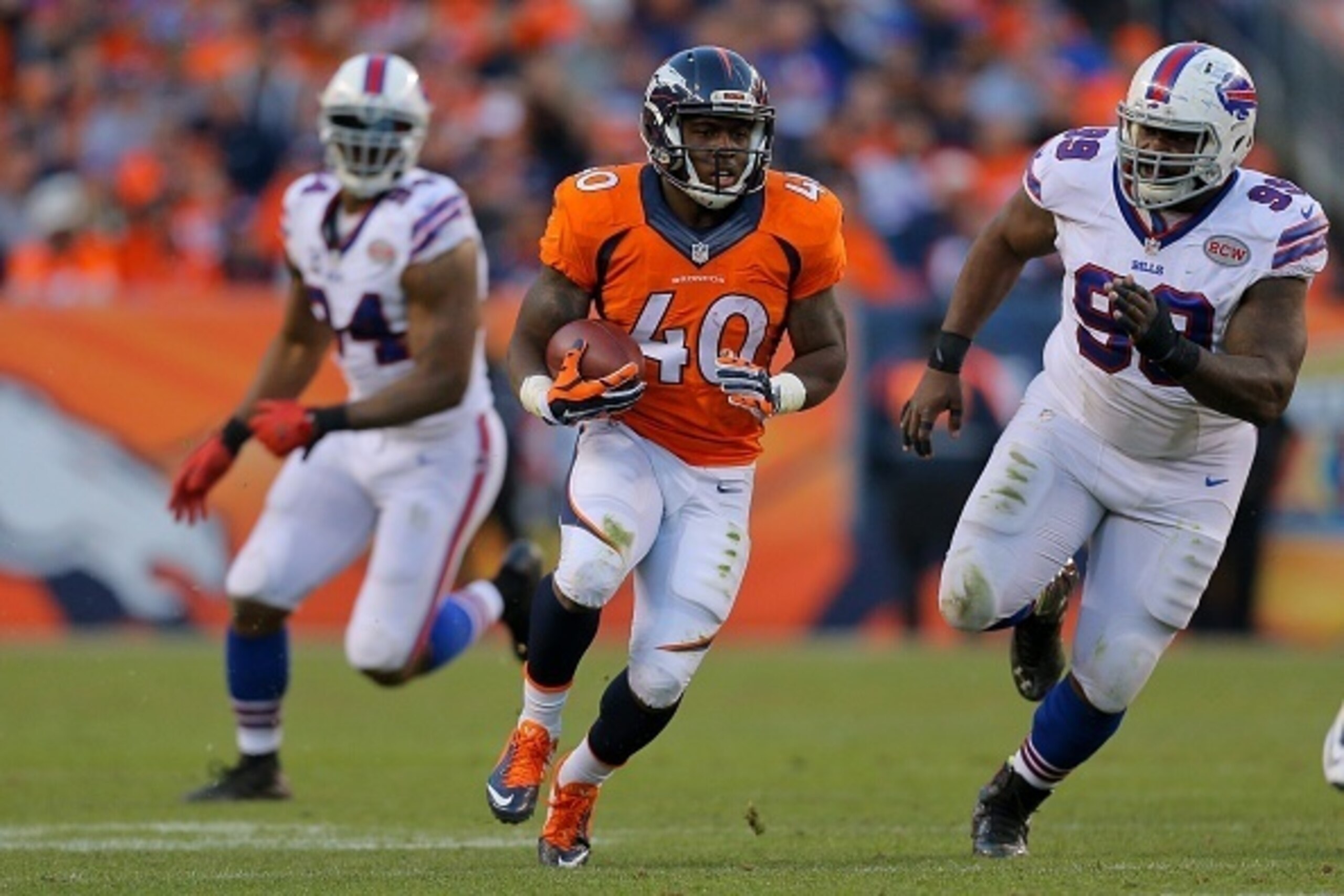 DENVER, CO - DECEMBER 7:  Running back Juwan Thompson #40 of the Denver Broncos runs with the ball during the third quarter before being tackled by defensive tackle Marcell Dareus #99 of the Buffalo Bills at Sports Authority Field Field at Mile High on De