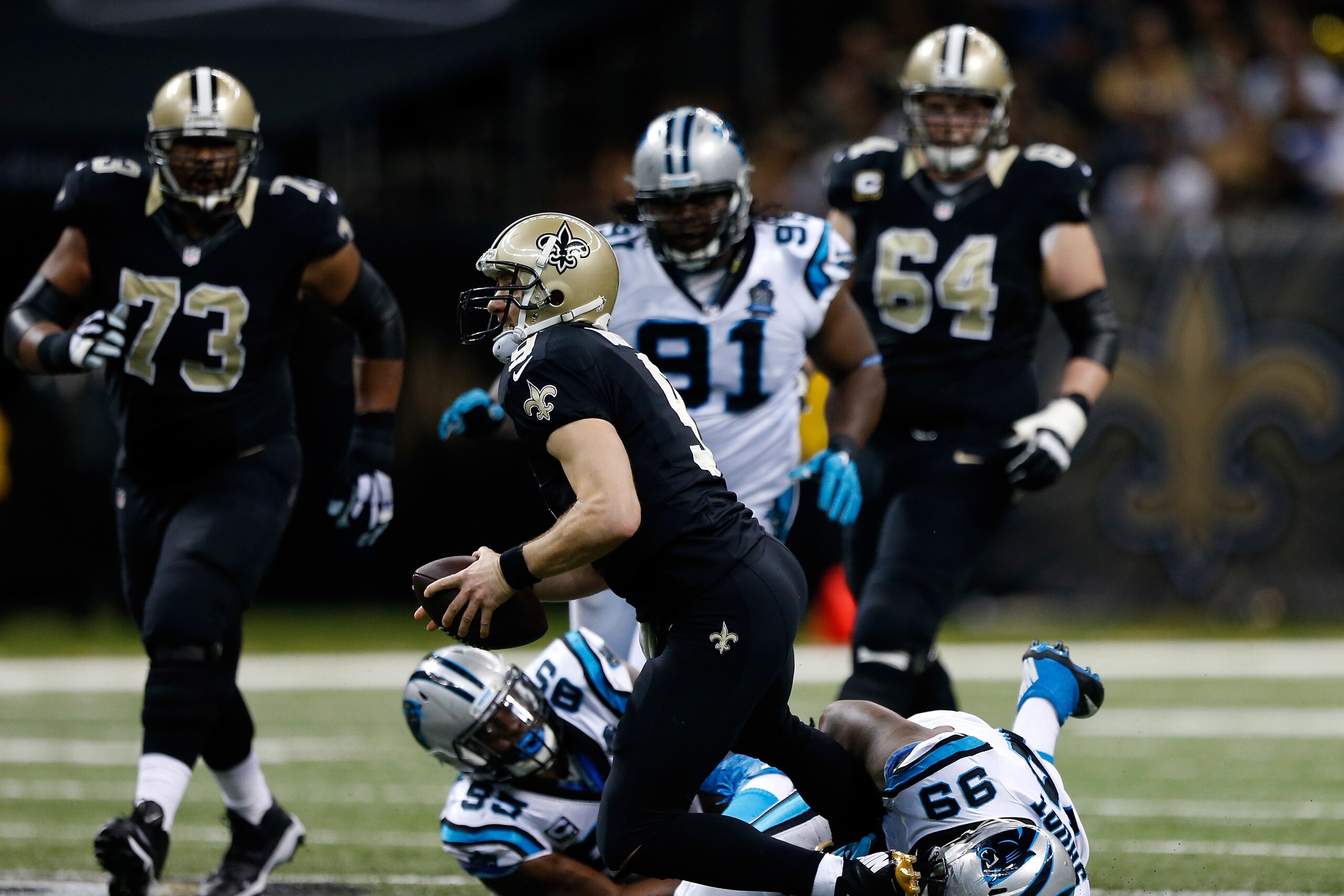 NEW ORLEANS, LA - DECEMBER 07:   Drew Brees #9 of the New Orleans Saints is sacked by Carolina Panthers defenders during the first quarter at Mercedes-Benz Superdome on December 7, 2014 in New Orleans, Louisiana.  (Photo by Sean Gardner/Getty Images)