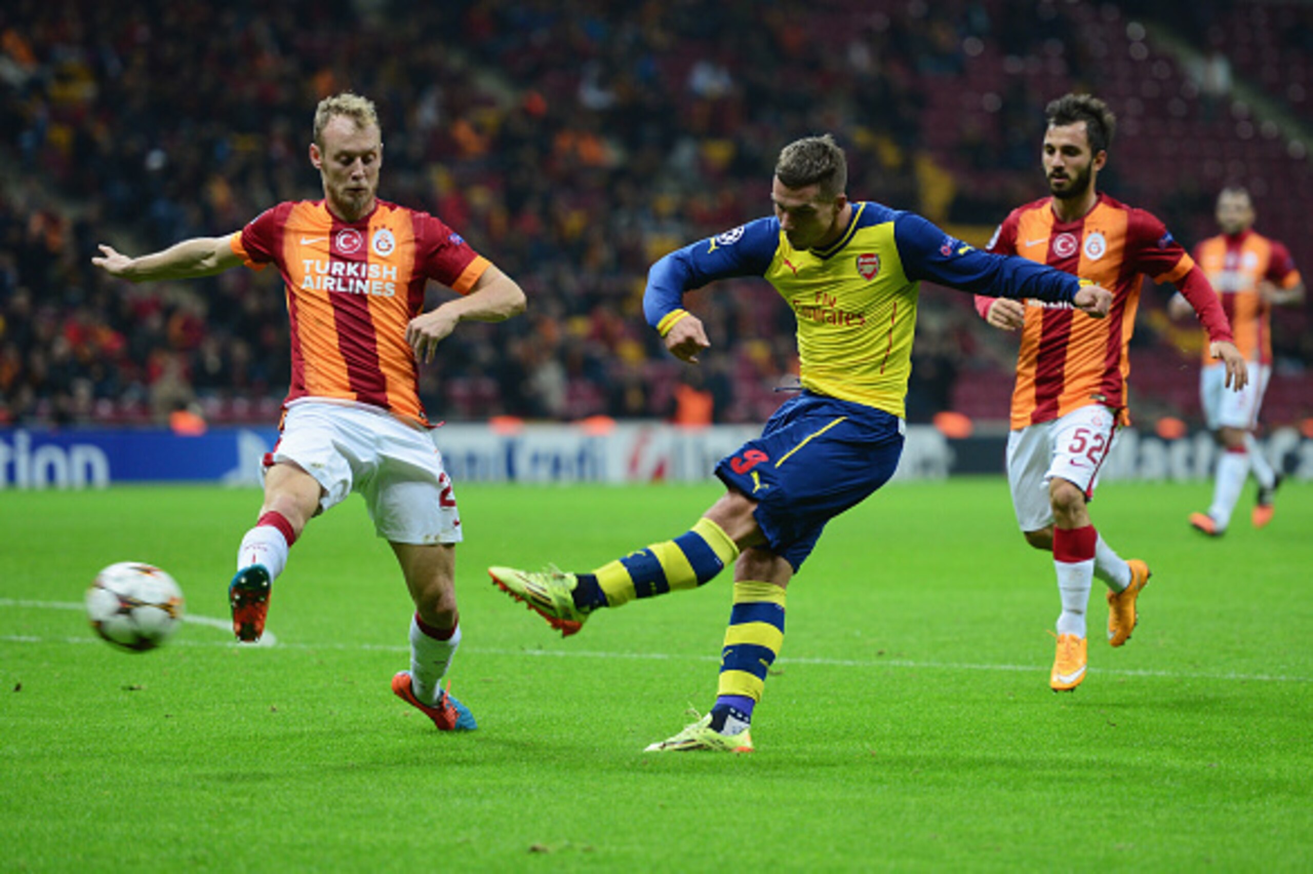 ISTANBUL, TURKEY - DECEMBER 09:  Lukas Podolski of Arsenal shoots past Semih Kaya of Galatasaray during the UEFA Champions League Group D match between Galatasaray AS and Arsenal FC at Ali Sami Yen Arena on December 9, 2014 in Istanbul, Turkey.  (Photo by