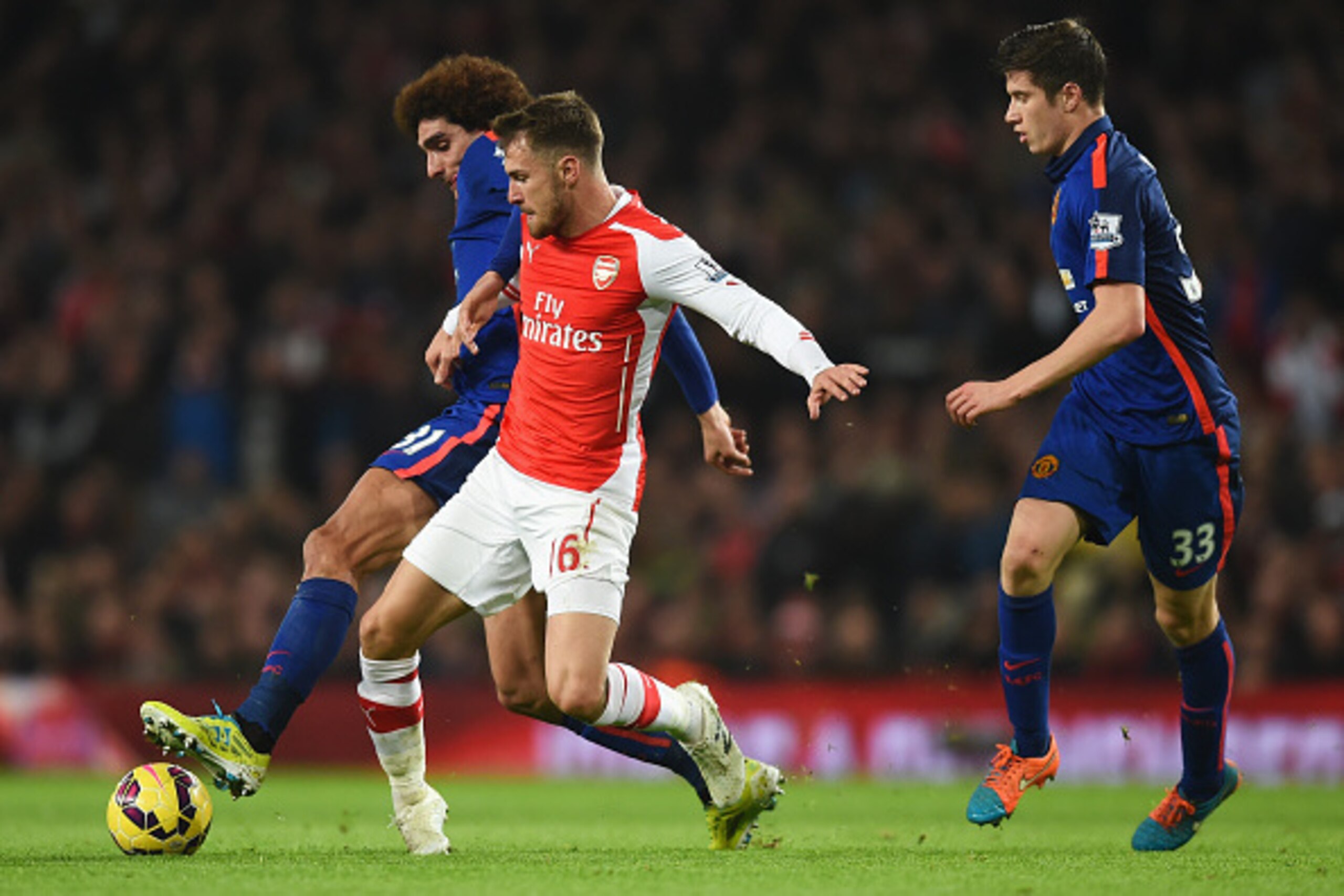 LONDON, ENGLAND - NOVEMBER 22: Marouane Fellaini of Manchester United challenges Aaron Ramsey of Arsenal watched by Paddy McNair of Manchester United during the Barclays Premier League match between Arsenal and Manchester United at Emirates Stadium on Nov