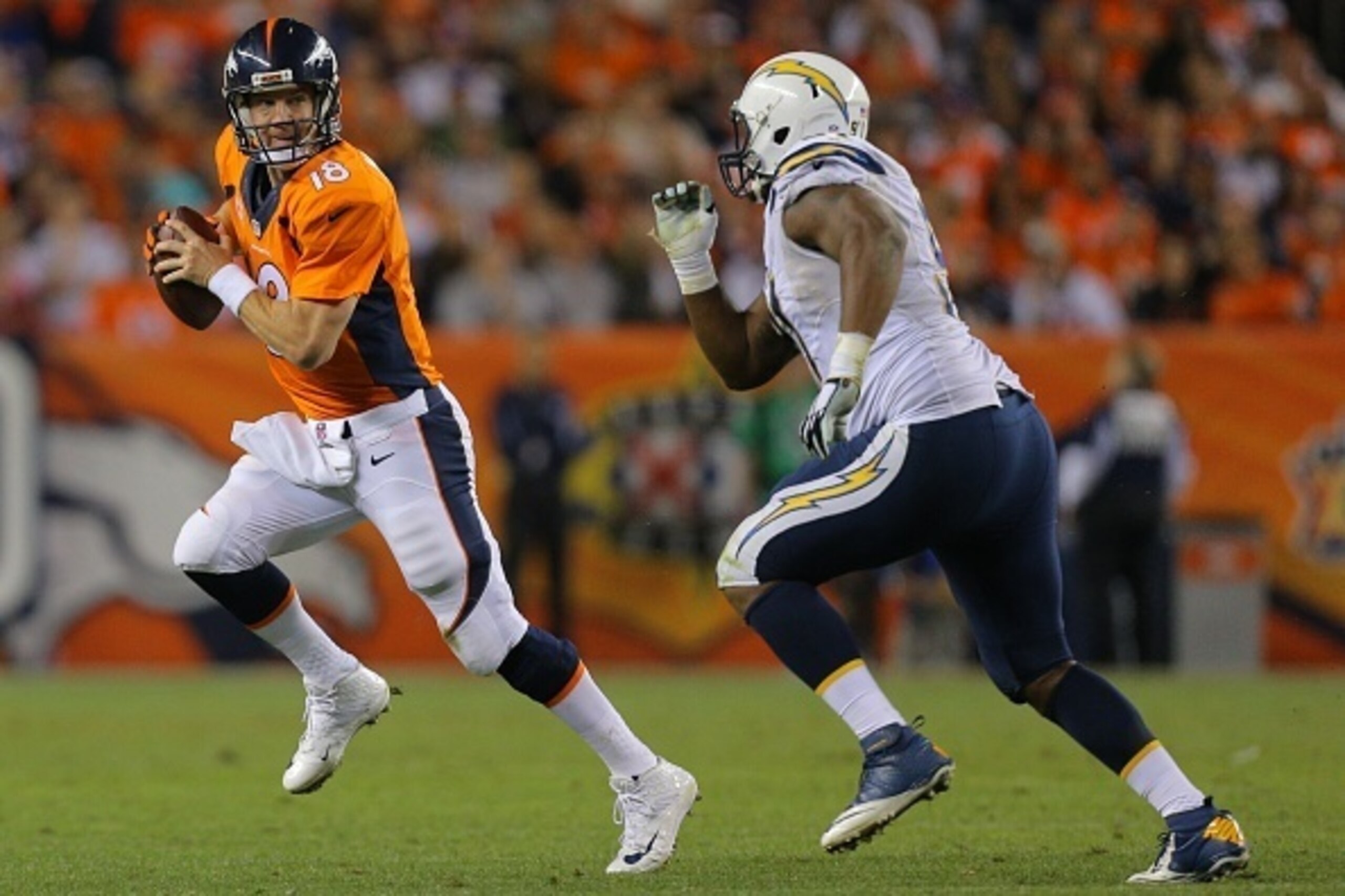 DENVER, CO - OCTOBER 23:  Quarterback Peyton Manning #18 of the Denver Broncos is pressured by defensive end Kendall Reyes #91 of the San Diego Chargers and scrambles out of the pocket during a game at Sports Authority Field at Mile High on October 23, 20