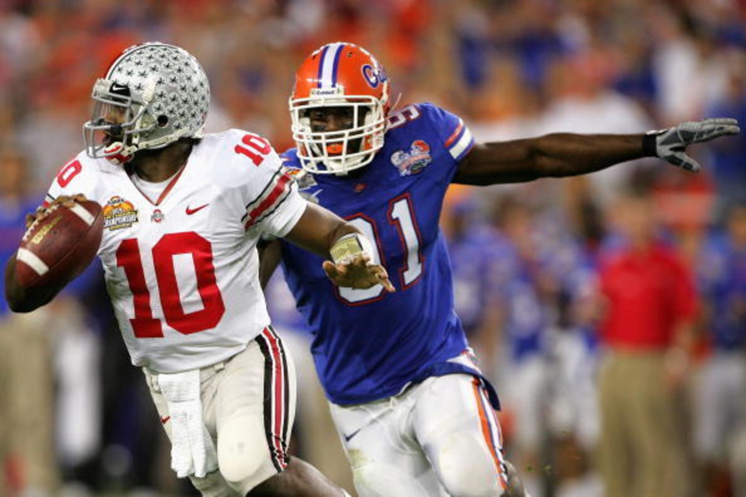 GLENDALE, AZ - JANUARY 08:  Quarterback Troy Smith #10 of the Ohio State Buckeyes scrambles with the ball under pressure from Derrick Harvey #91 of the Florida Gators during the 2007 Tostitos BCS National Championship Game at the University of Phoenix Sta