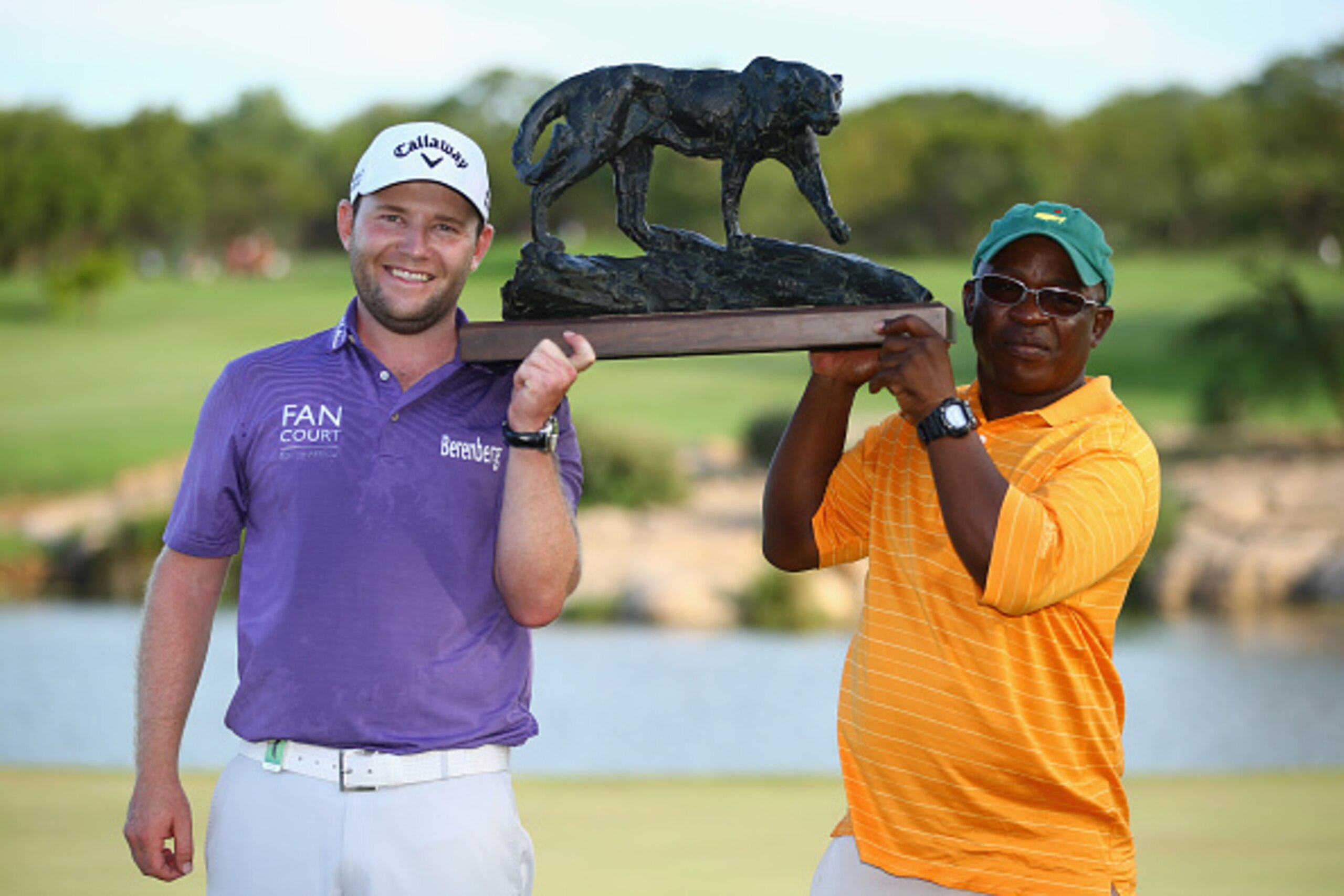 MALELANE, SOUTH AFRICA - DECEMBER 14:  Branden Grace of South Africa holds the trophy with caddy Zack Rasego after securing victory in the final round of the Alfred Dunhill Championship at Leopard Creek Country Golf Club on December 14, 2014 in Malelane, 