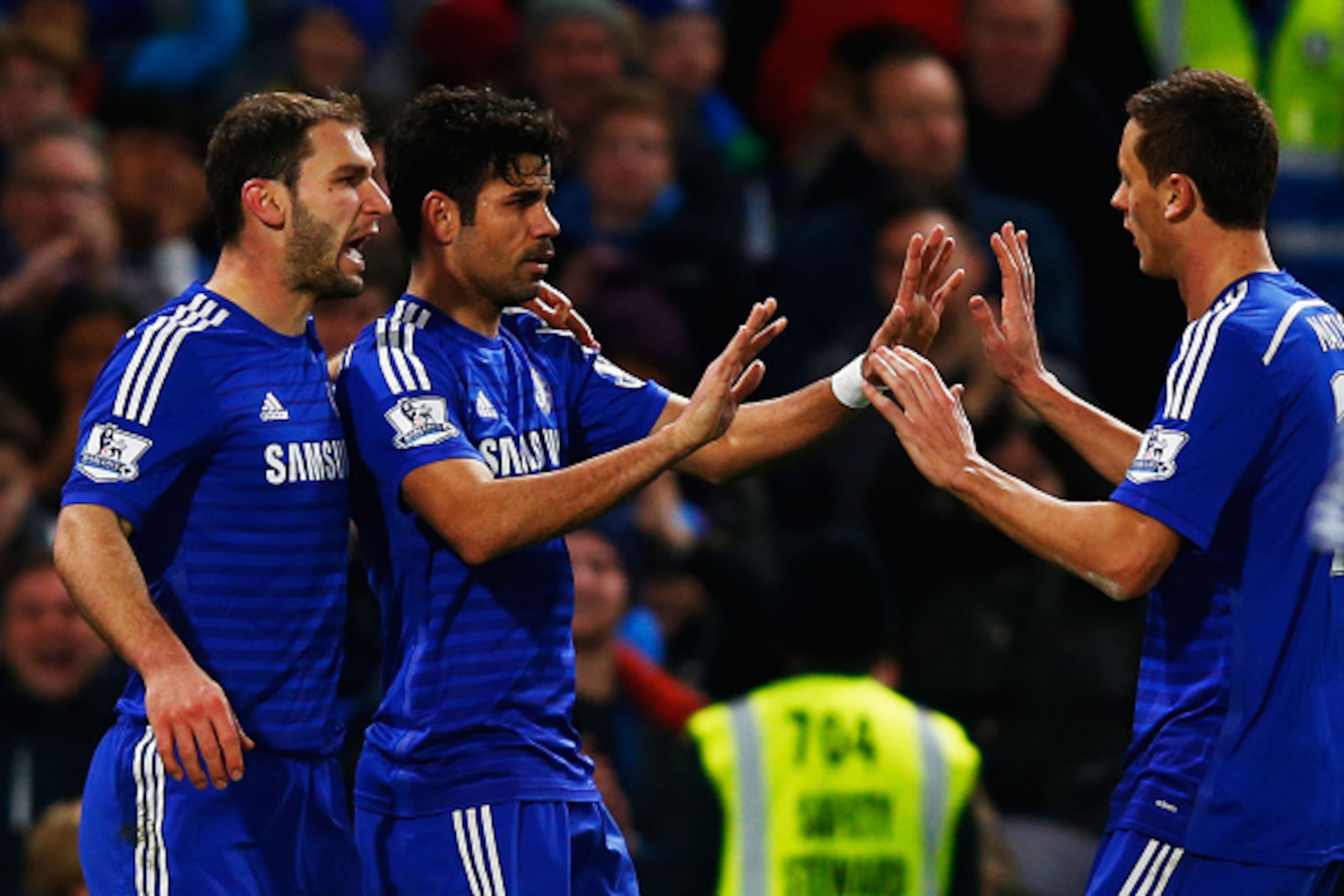LONDON, ENGLAND - DECEMBER 13:  Diego Costa of Chelsea (C) celebrates with team mates Branislav Ivanovic (L) and Nemanja Matic (R) as he scores their second goal during the Barclays Premier League match between Chelsea and Hull City at Stamford Bridge on 