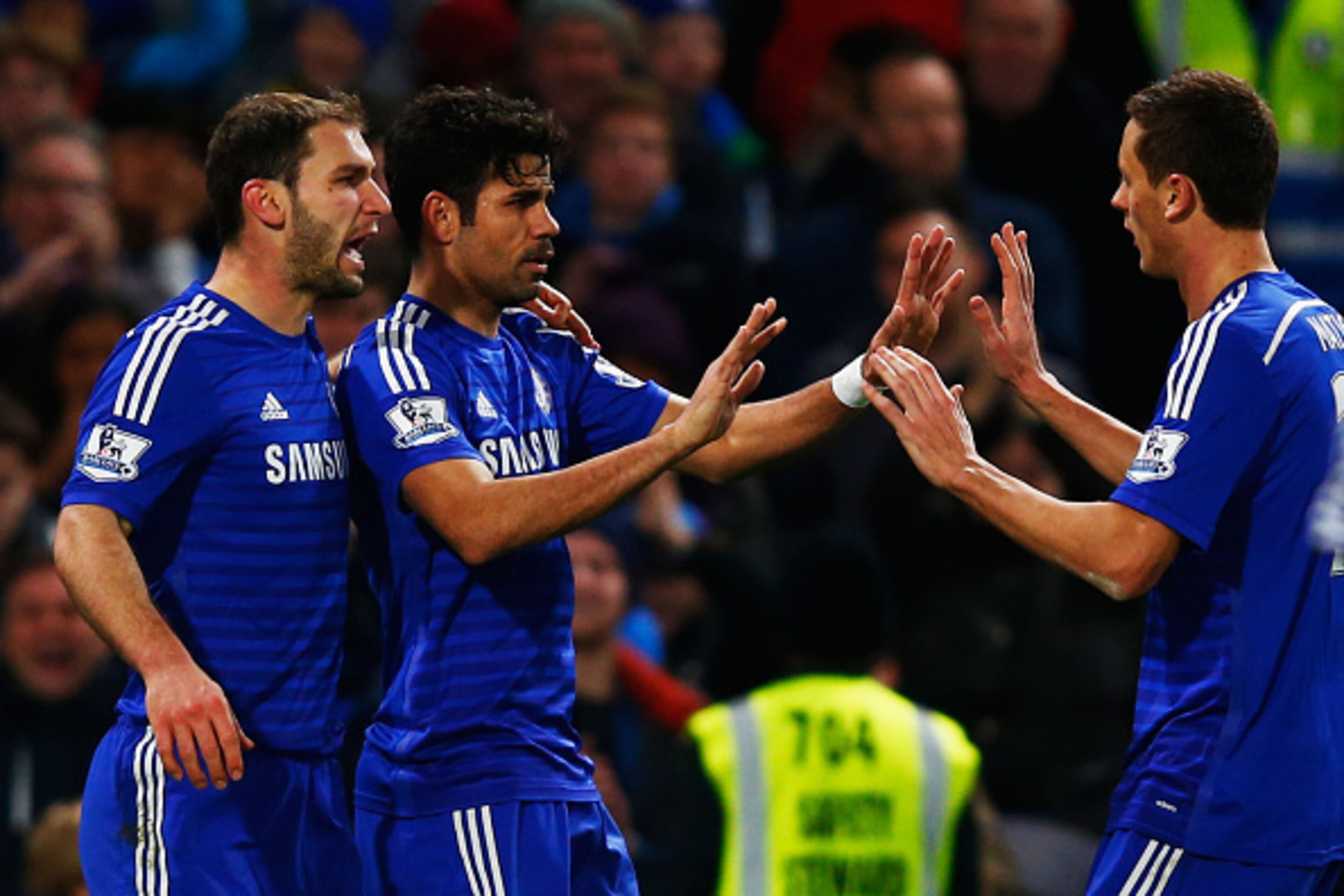 LONDON, ENGLAND - DECEMBER 13:  Diego Costa of Chelsea (C) celebrates with team mates Branislav Ivanovic (L) and Nemanja Matic (R) as he scores their second goal during the Barclays Premier League match between Chelsea and Hull City at Stamford Bridge on 