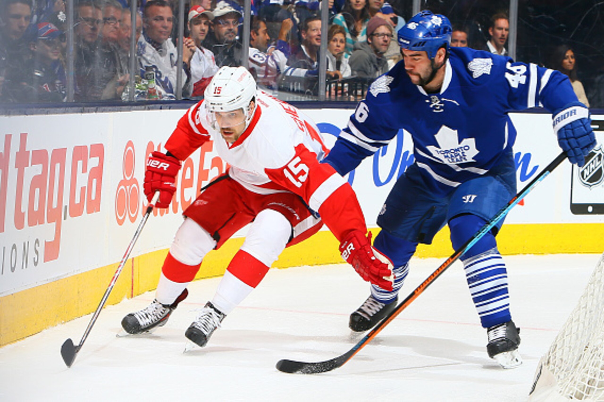 TORONTO , ON - NOVEMBER 22: Roman Polak #46 of the Toronto Maple Leafs takes out Riley Sheahan #15 of the Detroit Red Wings during NHL game action November 22, 2014 at the Air Canada Centre in Toronto, Ontario, Canada. (Photo by Graig Abel/NHLI via Getty 