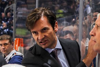 WINNIPEG, CANADA - DECEMBER 3: Head Coach Dallas Eakins of the Edmonton Oilers discusses strategy with players at the bench during a third period timeout against the Winnipeg Jets on December 3, 2014 at the MTS Centre in Winnipeg, Manitoba, Canada. The Je