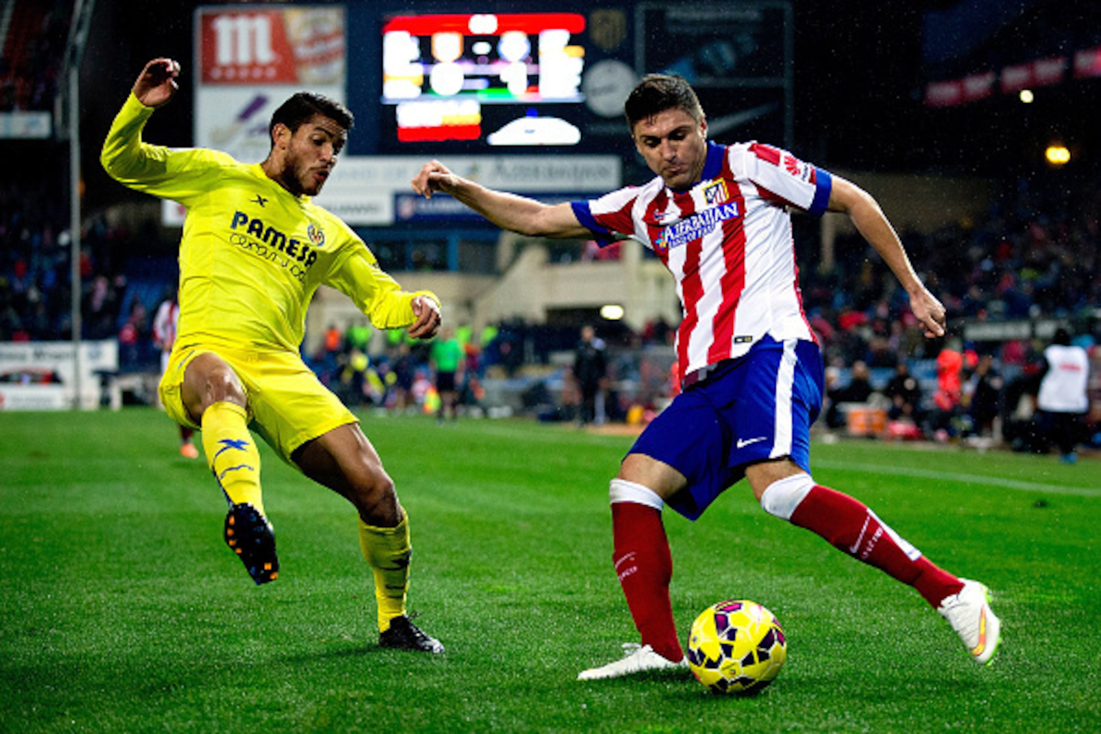MADRID, SPAIN - DECEMBER 14: Guilherme Madalena Siqueira (R) competes for the ball with J. Dos Santos (L) of Villarreal CF during the La Liga match between Club Atletico de Madrid and Villarreal CF at Vicente Calderon Stadium on December 14, 2014 in Madri
