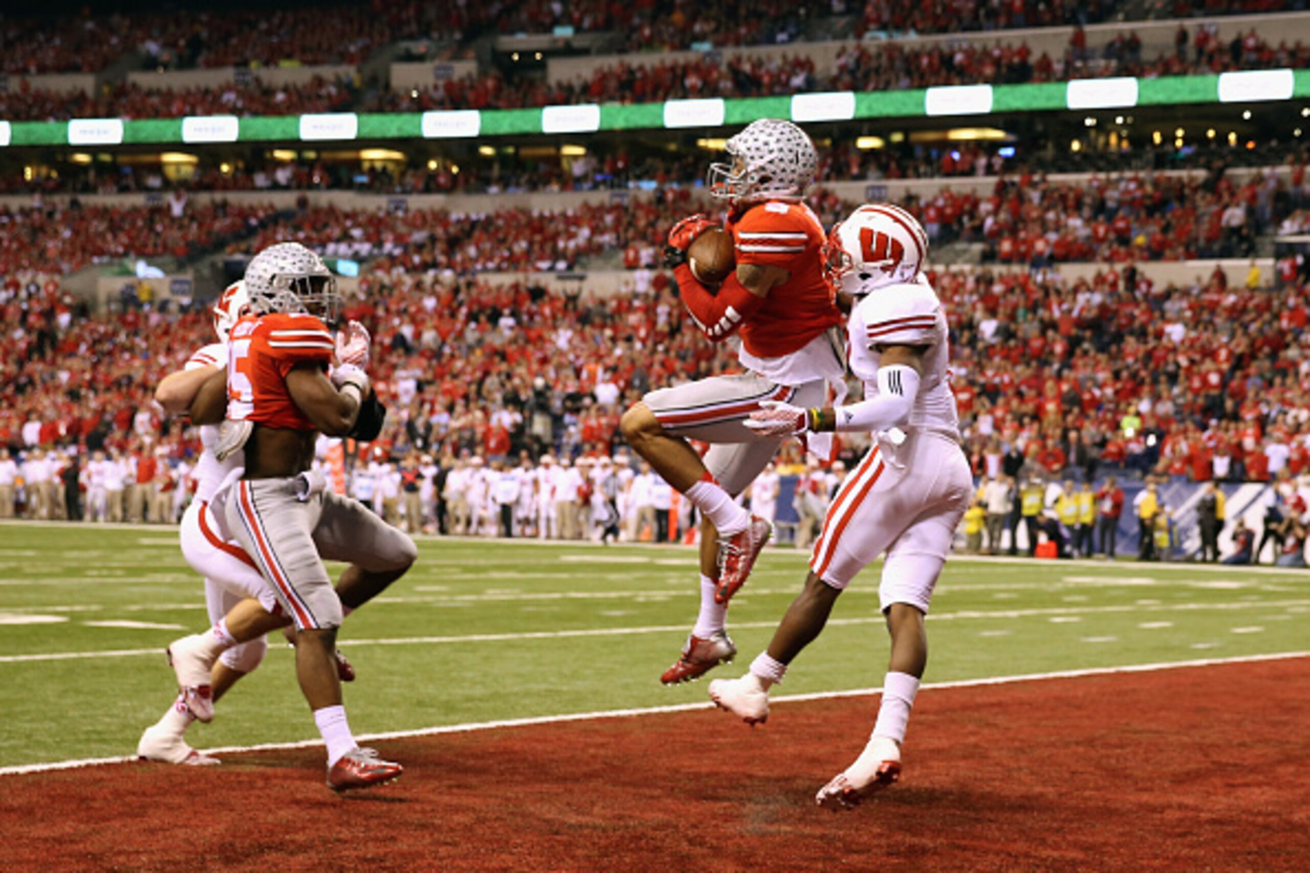 INDIANAPOLIS, IN - DECEMBER 06:  Devin Smith #9 of the Ohio State Buckeyes catches the ball over Sojourn Shelton #8 of the Wisconsin Badgers to score a touchdown in the first quarter of the Big Ten Championship game at Lucas Oil Stadium on December 6, 201