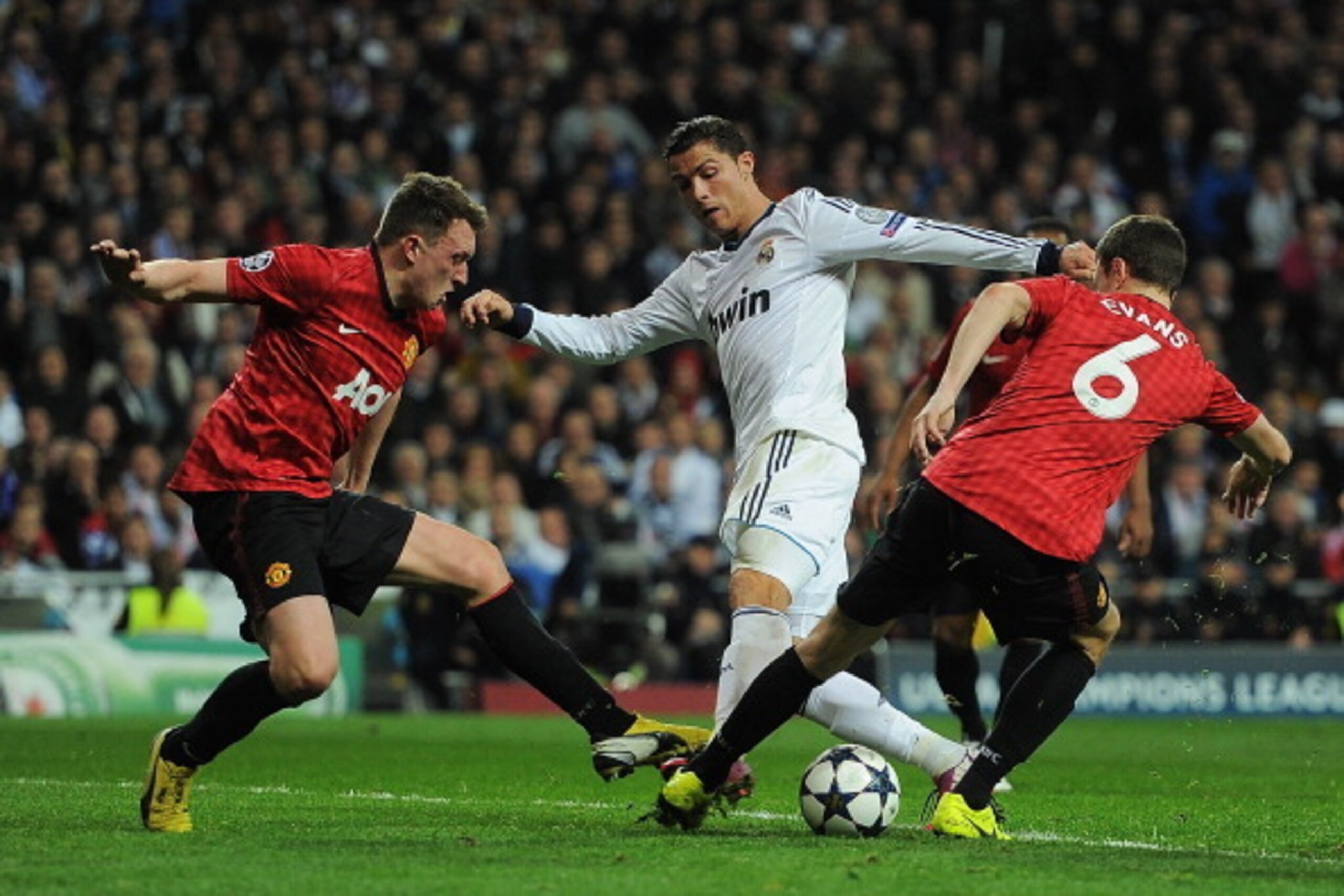 MADRID, SPAIN - FEBRUARY 13: Cristiano Ronaldo of Real Madrid is put under pressure by Jonny Evans and Phil Jones of Manchester United during the UEFA Champions League Round of 16 first leg match between Real Madrid and Manchester United at Estadio Sant MADRID, SPAIN - FEBRUARY 13: Cristiano Ronaldo of Real Madrid is put under pressure by Jonny Evans and Phil Jones of Manchester United during the UEFA Champions League Round of 16 first leg match between Real Madrid and Manchester United at Estadio Sant